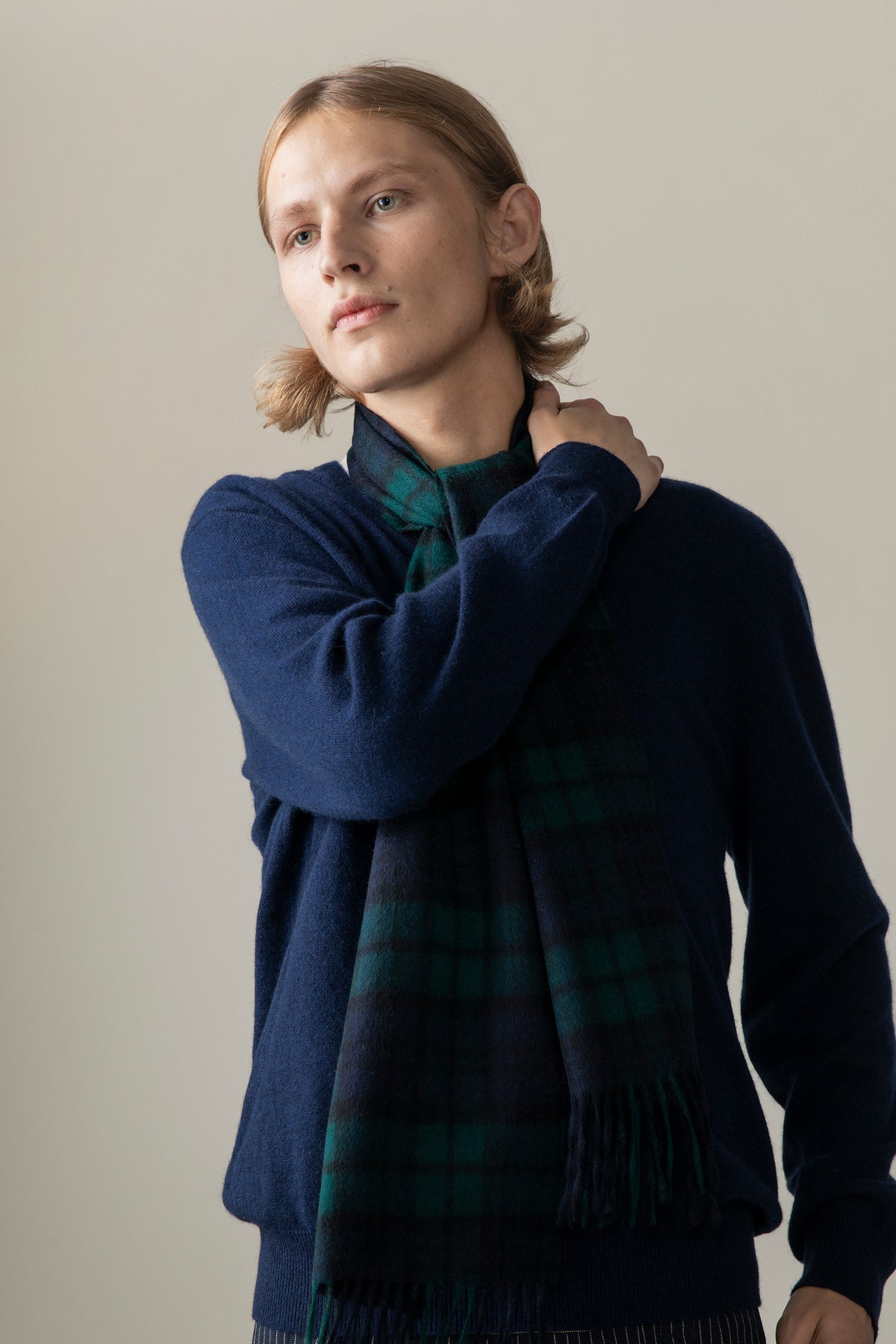 Heritage Tartan Cashmere Scarf - Blackwatch worn over a navy sweater, showing the green and navy tartan pattern and fringed ends