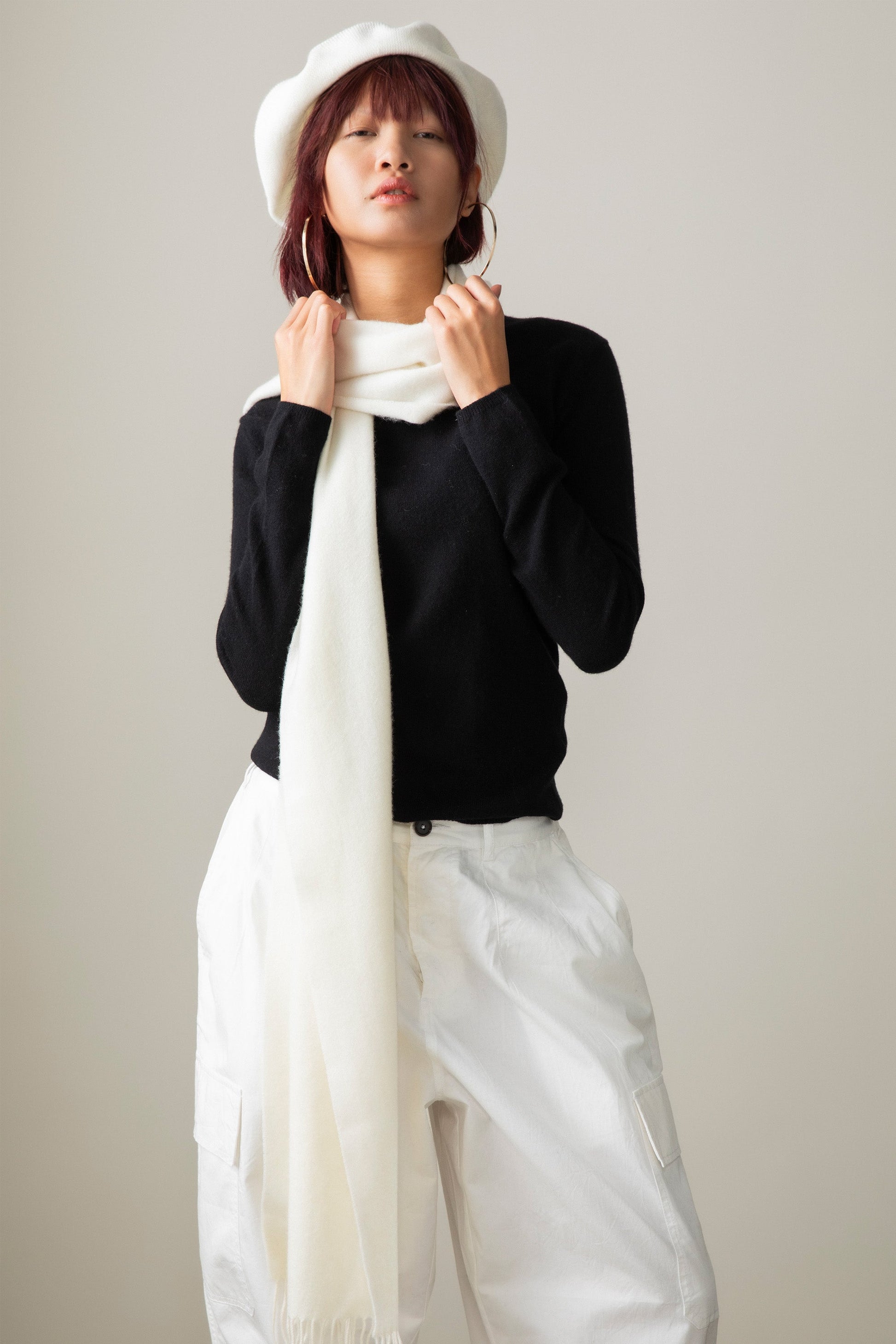 Solid Cashmere Wide Scarf in Soft Cream draped around the neck over a black sweater, styled with a white beret