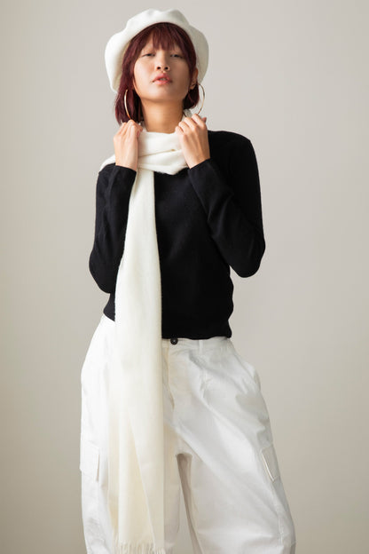 Solid Cashmere Wide Scarf in Soft Cream draped around the neck over a black sweater, styled with a white beret
