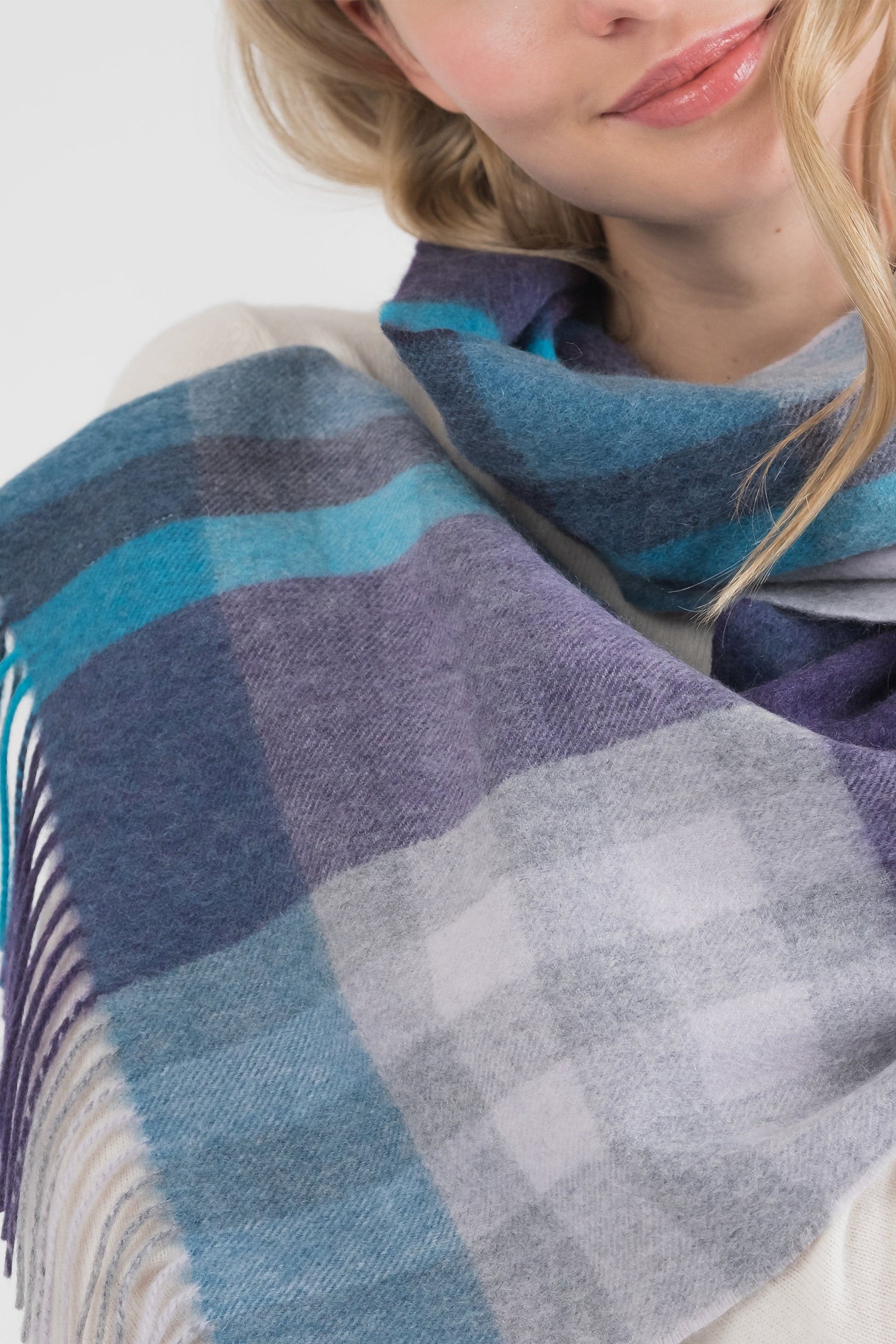 Tartan 2 Cashmere Wide Scarf in Blue worn draped around the neck, showing plaid pattern in teal, purple, and grey with fringe detail