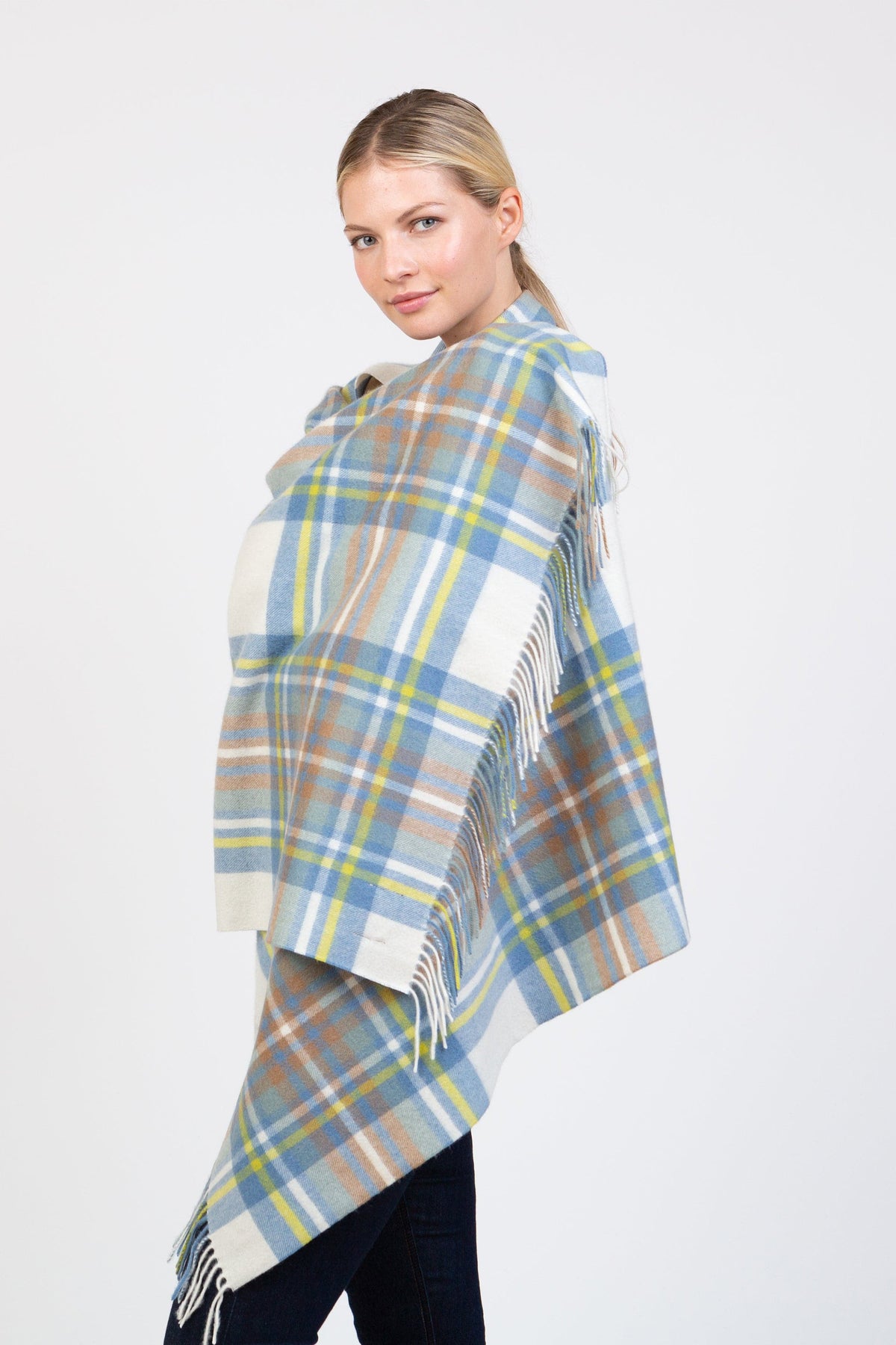 Heritage Tartan Cashmere Stole in Muted Blue Stewart draped over shoulders, showing soft plaid in blue, cream, yellow, and brown with fringed edges