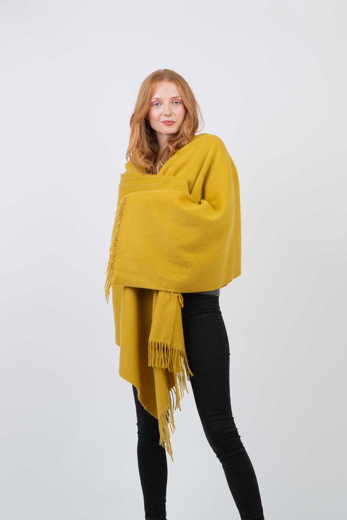 Solid Cashmere Stole in Sulphur Green worn wrapped around shoulders, showing soft texture and fringed edges