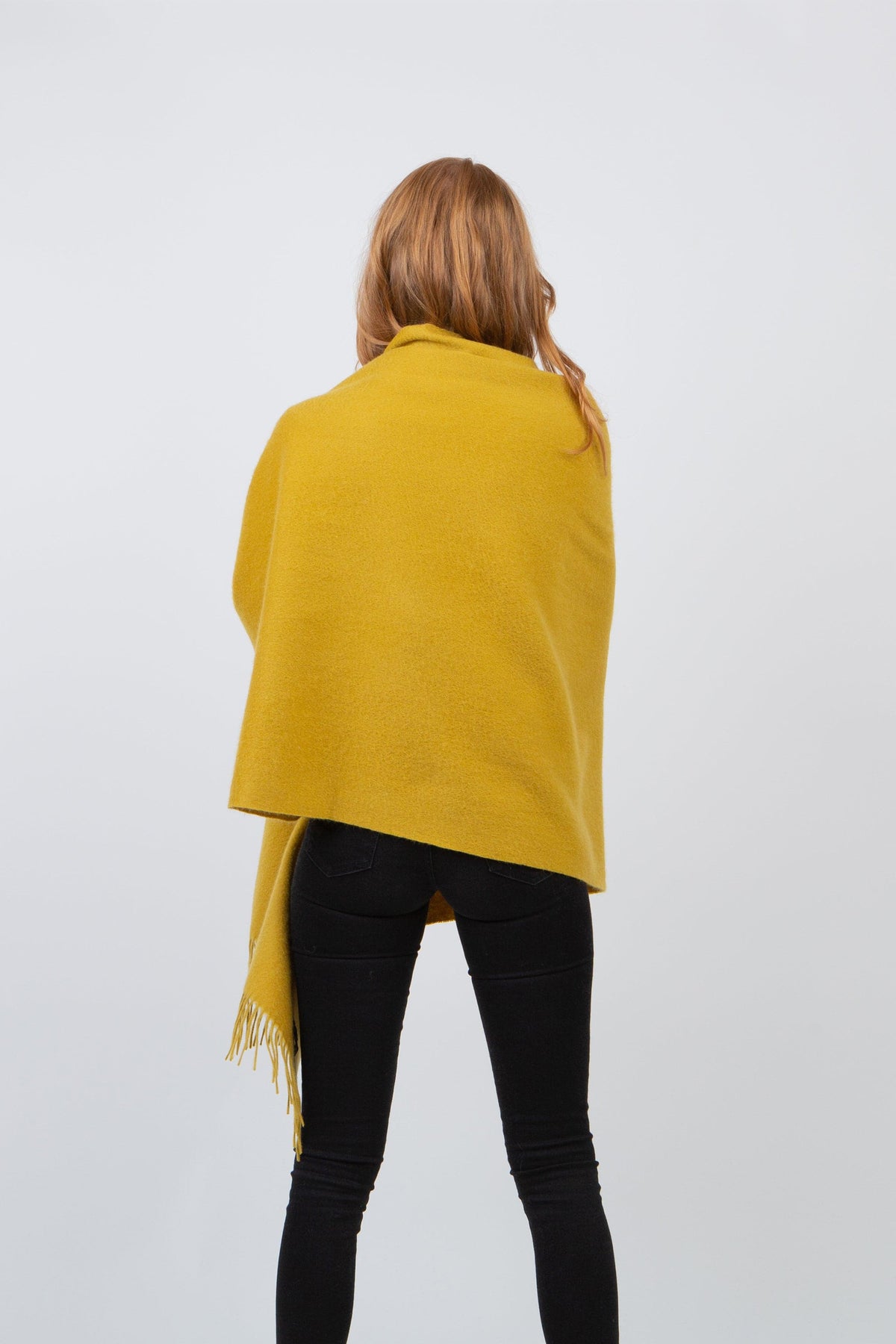 Back view of the Solid Cashmere Stole in Sulphur Green draped over shoulders, showing full coverage and fringed hem detail
