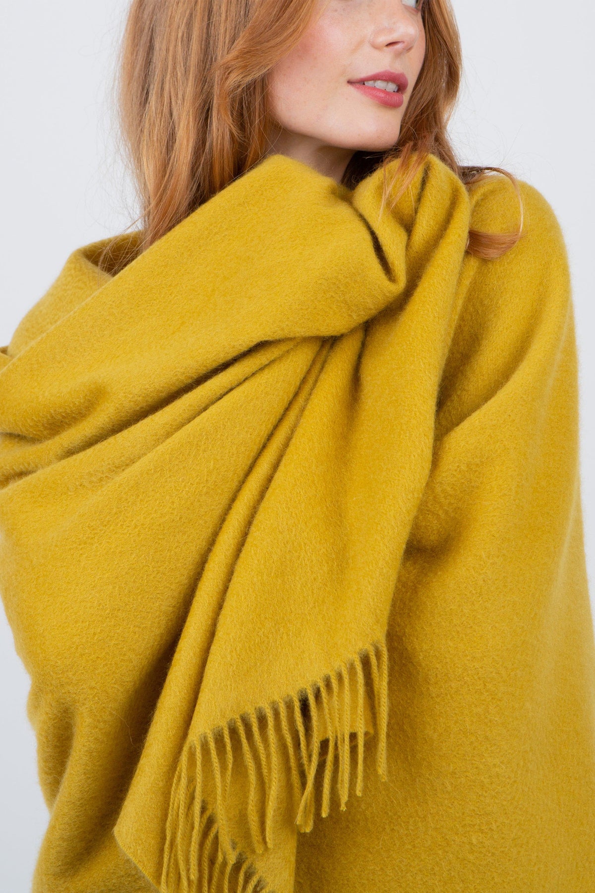 Solid Cashmere Stole in Sulphur Green wrapped loosely around the neck, showing soft brushed texture and fringed ends