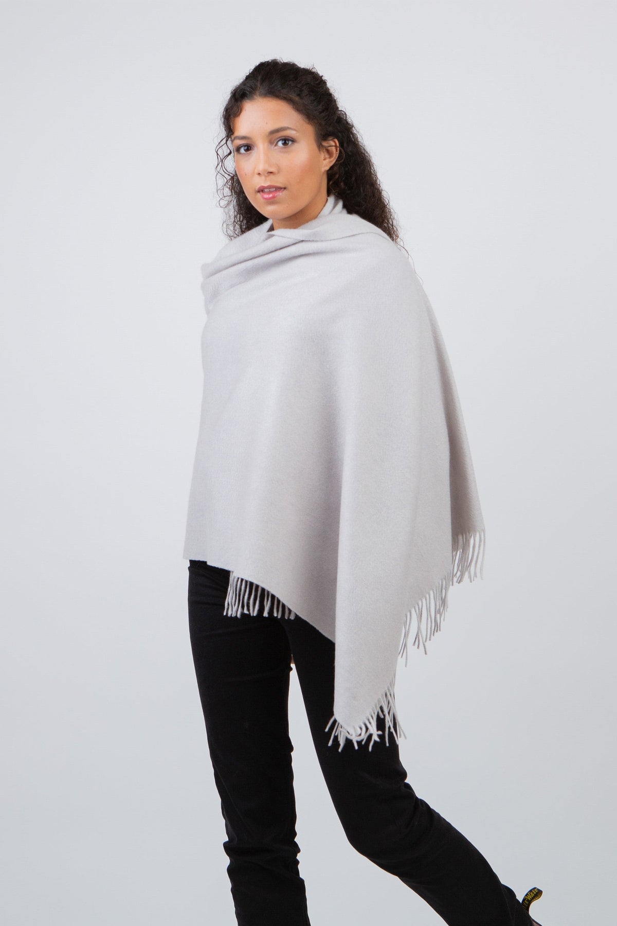 Solid Cashmere Stole in Potash, a soft light grey wrap with fringed edges, draped over the shoulders as a shawl