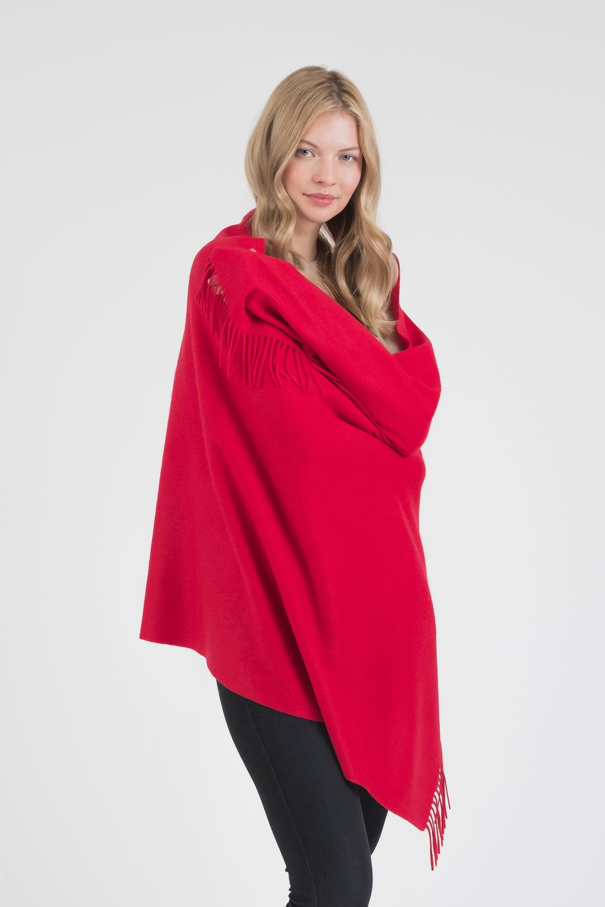 Model wrapping the Solid Cashmere Stole in Red around her shoulders, showing the generous size and fringed edges