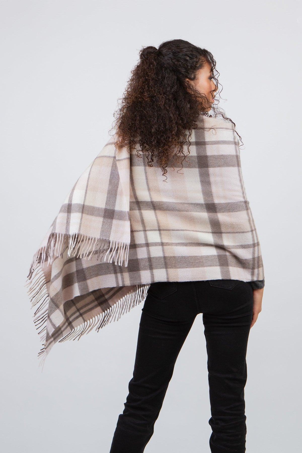 Back view of model wearing Square Check Cashmere Stole in Natural, showing full plaid pattern drape and fringed edges