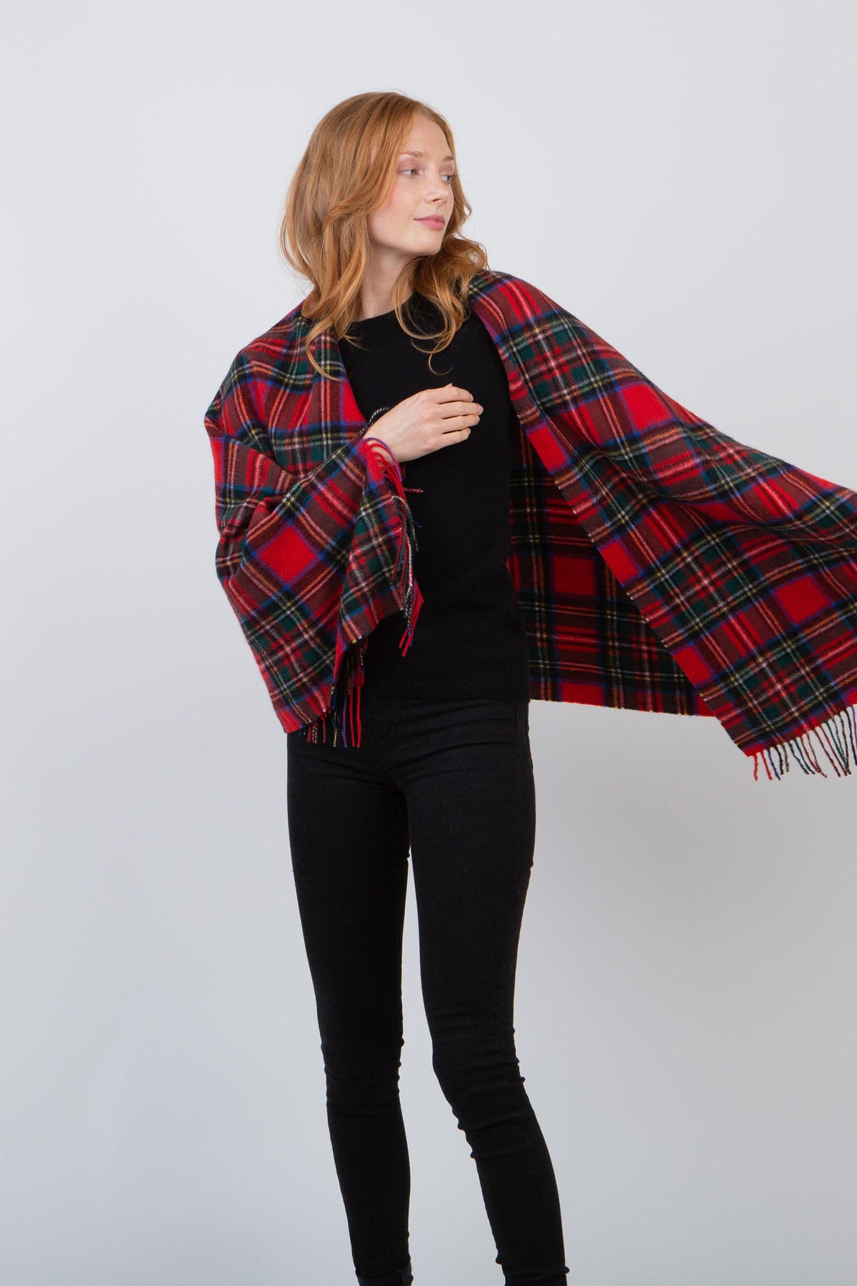 Heritage Tartan Cashmere Stole in Royal Stewart draped over shoulders, featuring red tartan plaid pattern with fringed edges