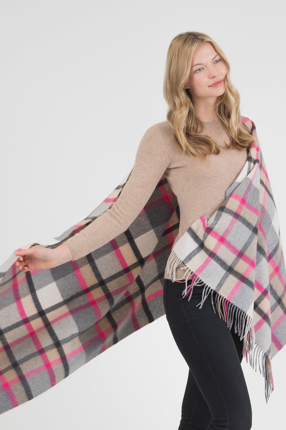 Model draping the Princeton Check Cashmere Stole in Pink, showing the full plaid pattern in grey, beige, and vibrant pink with fringed edges