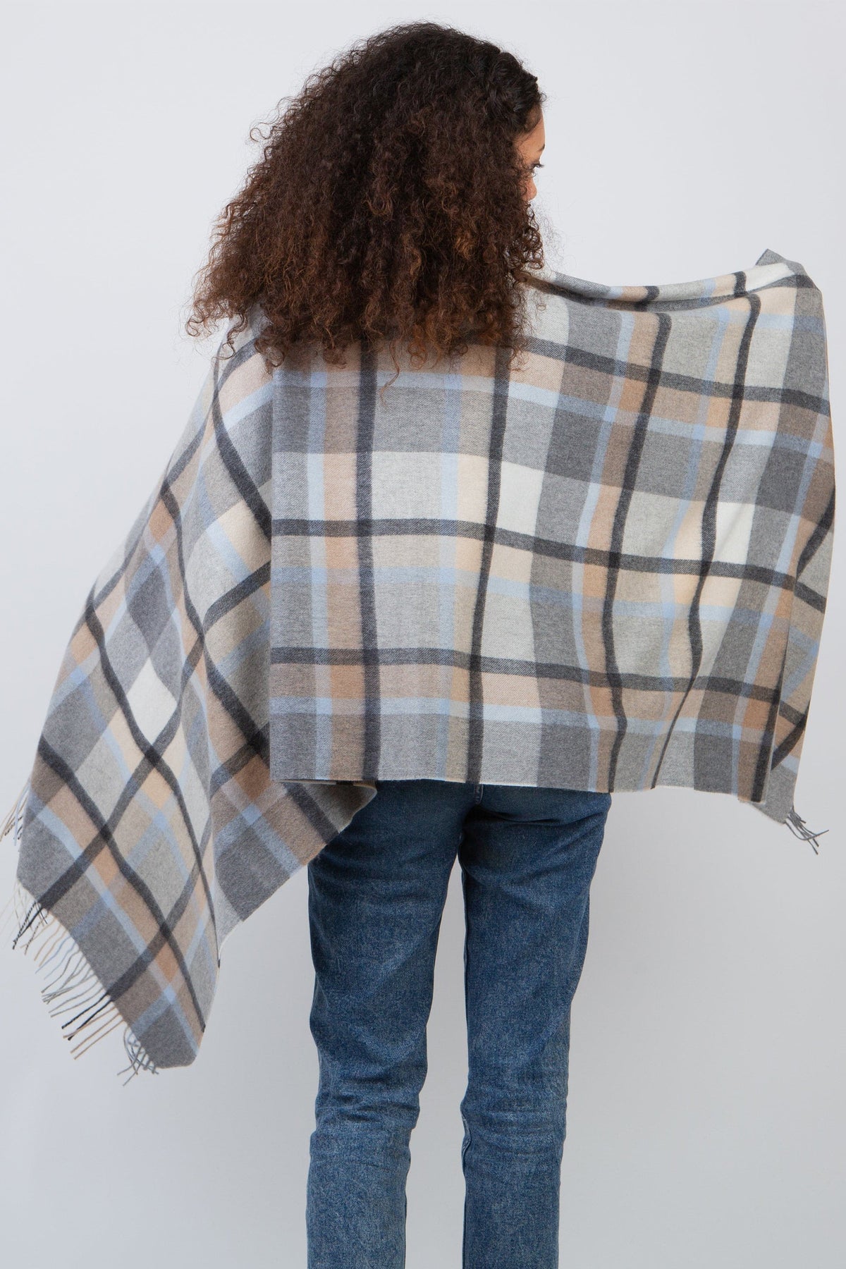 Back view of Princeton Check Cashmere Stole in Blue worn as a poncho, showing grey, blue, and beige plaid pattern with fringe hem