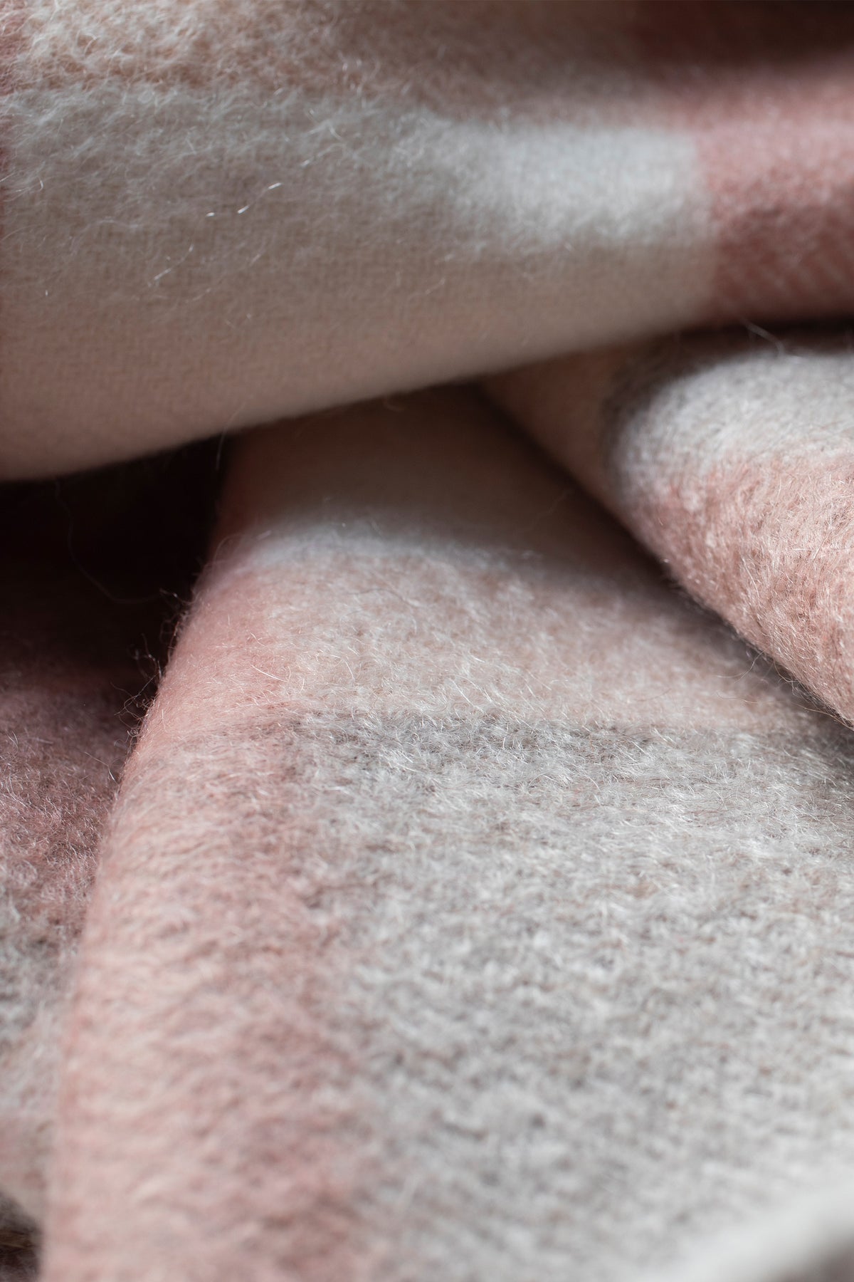 Close-up of the soft brushed cashmere texture on the Contemporary Check Cashmere Stole in Cameo pink and grey tones