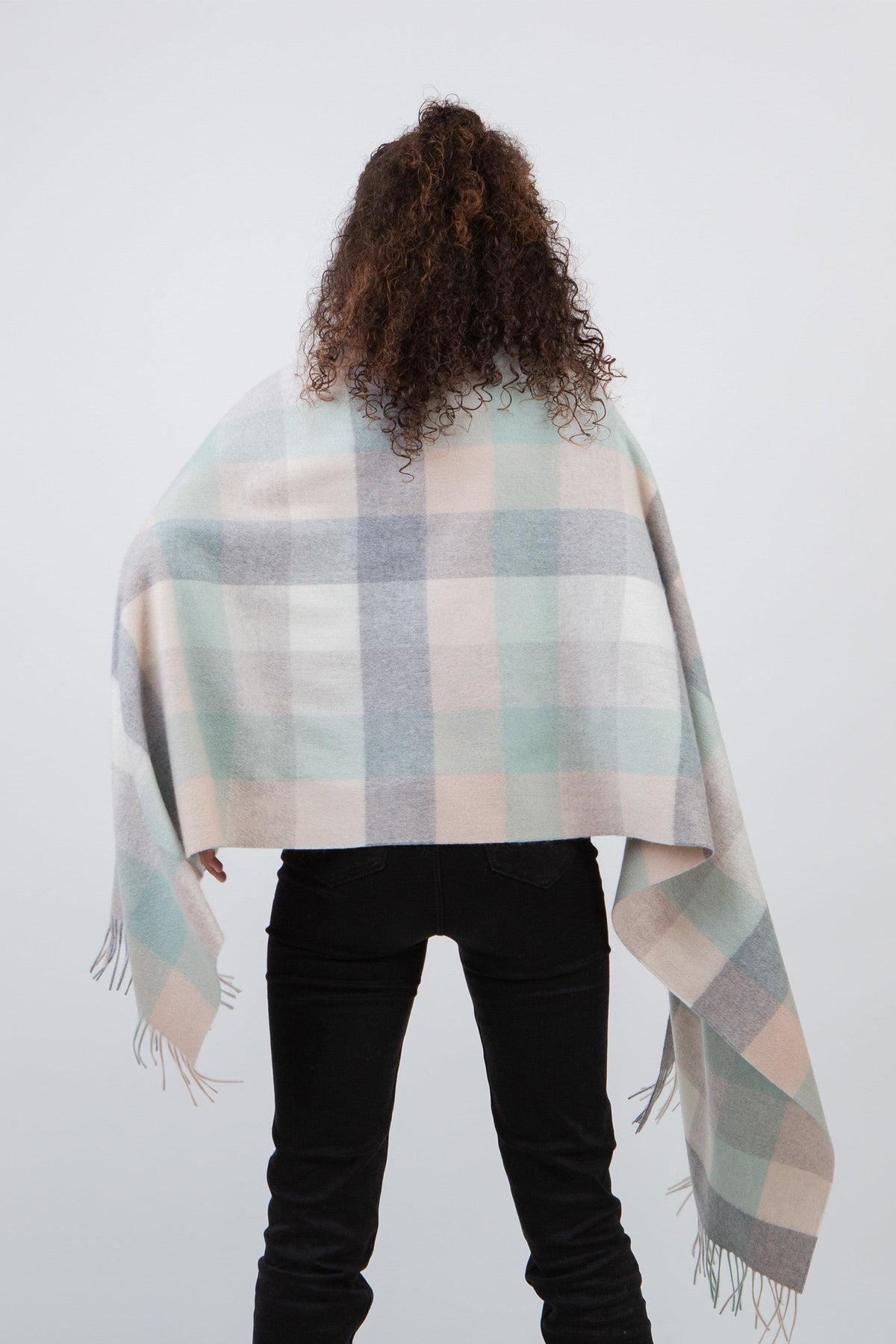 Back view of the 5 Square Check Cashmere Stole in Brume draped over shoulders, showing pastel plaid pattern and fringed edges