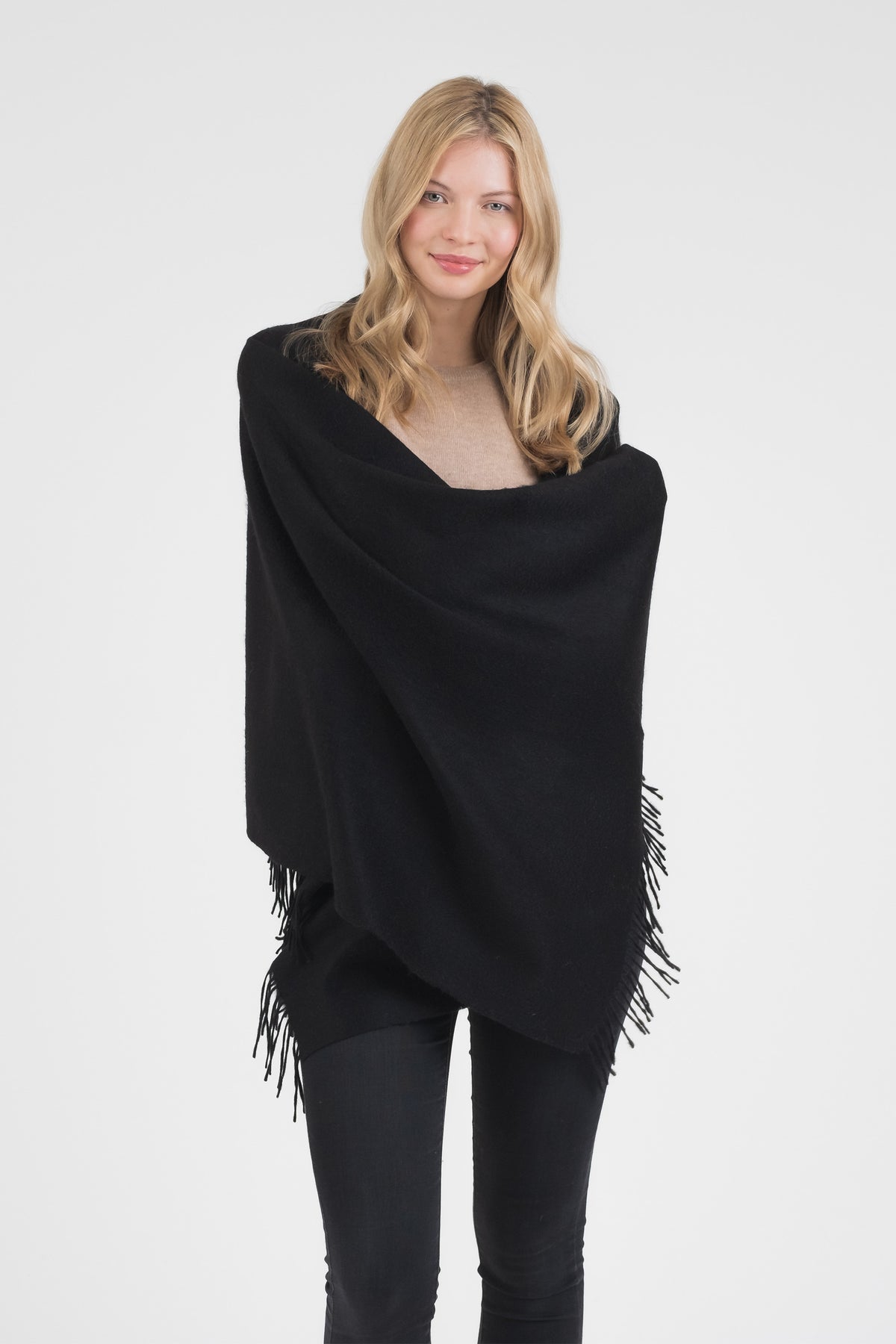 Model wearing the Solid Cashmere Stole in black wrapped around shoulders, showing soft texture and fringed hem detail