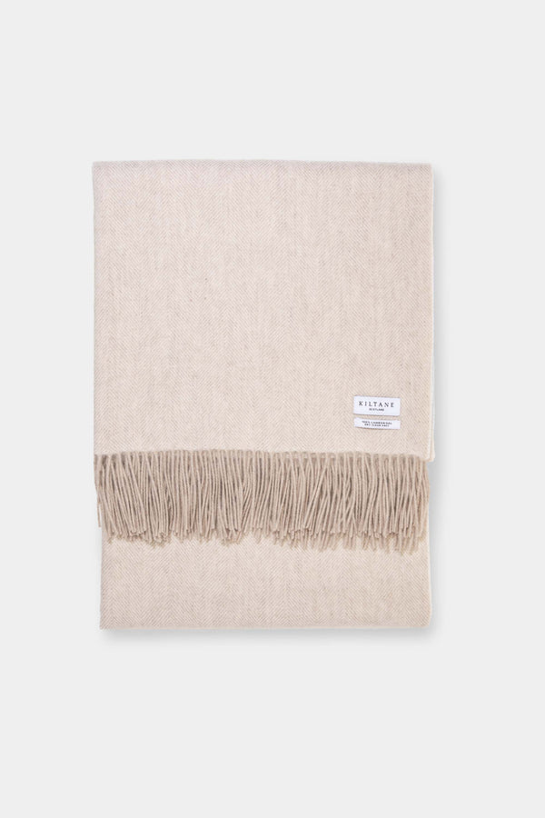 Kiltane Herringbone Lambswool Throw in Sand, folded flat showing soft beige herringbone weave and fringed edges