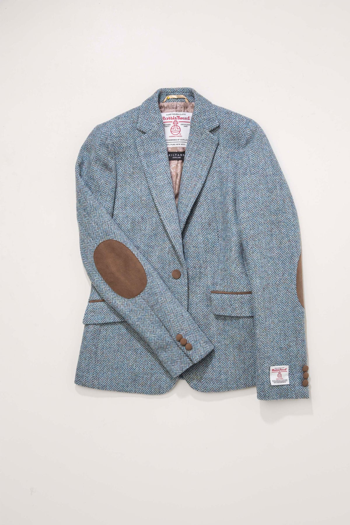 Women's Harris Tweed Janice Blazer in light blue herringbone mix laid flat showing brown suede elbow patches and interior labels
