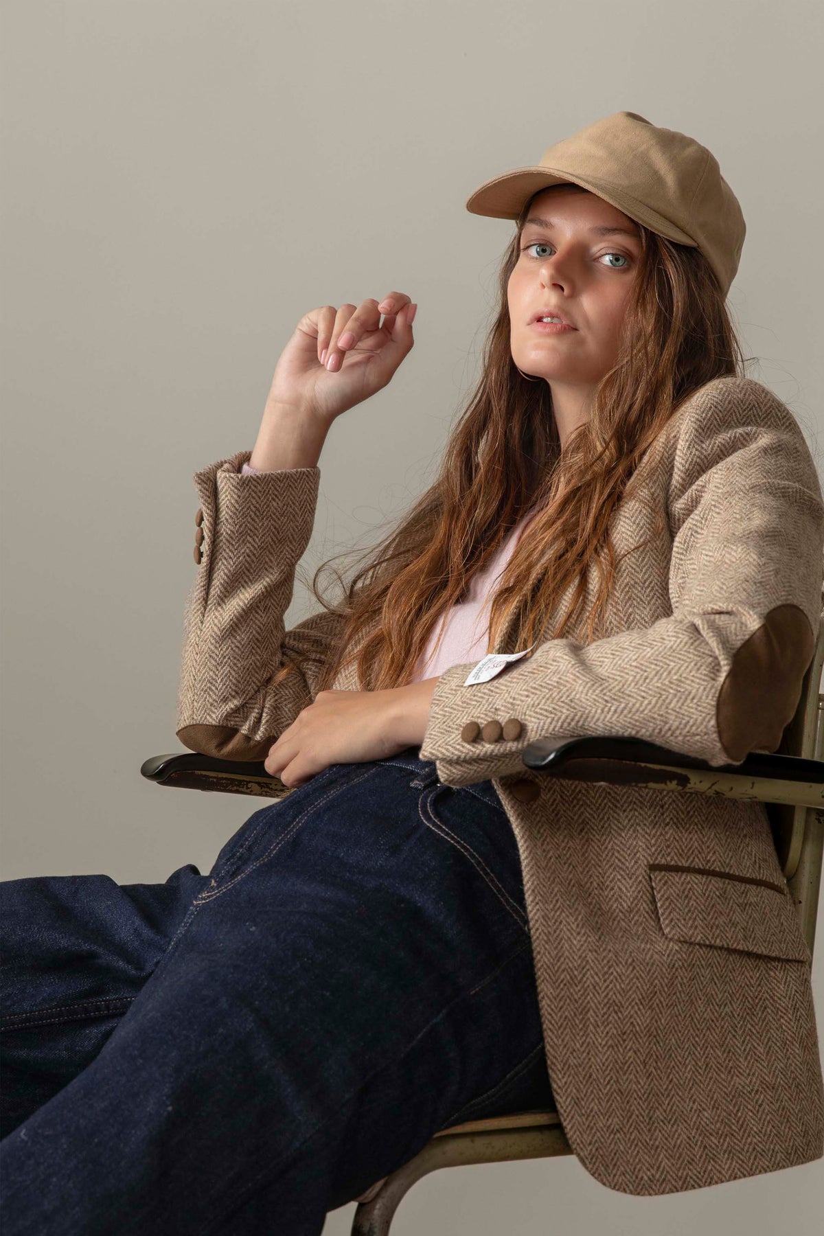 Women's Harris Tweed Janice Blazer in light beige herringbone worn seated, showing suede elbow patches and cuff button details
