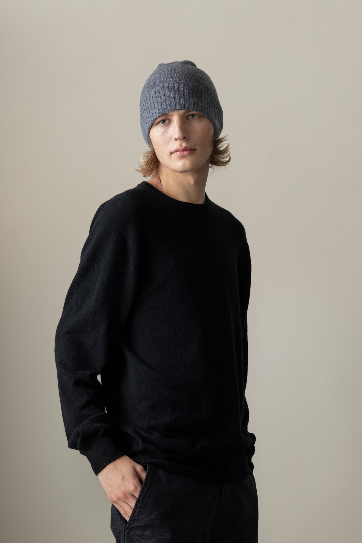 Unisex Cashmere Plain Beanie Hat in Derby Grey with ribbed fold-up cuff, worn by model with black crewneck sweater