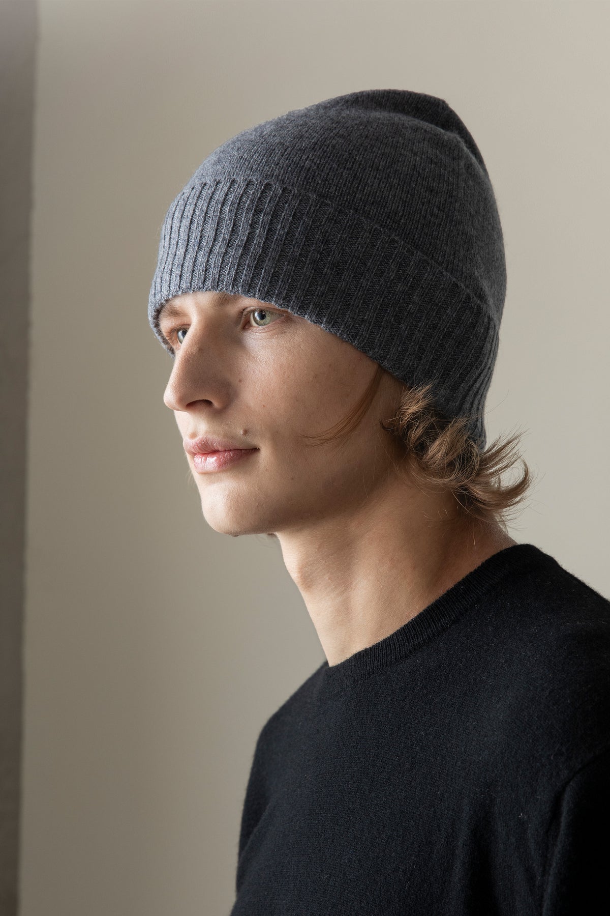 Unisex Cashmere Plain Beanie Hat in Derby Grey shown on model in profile view, highlighting the ribbed brim and slim fit