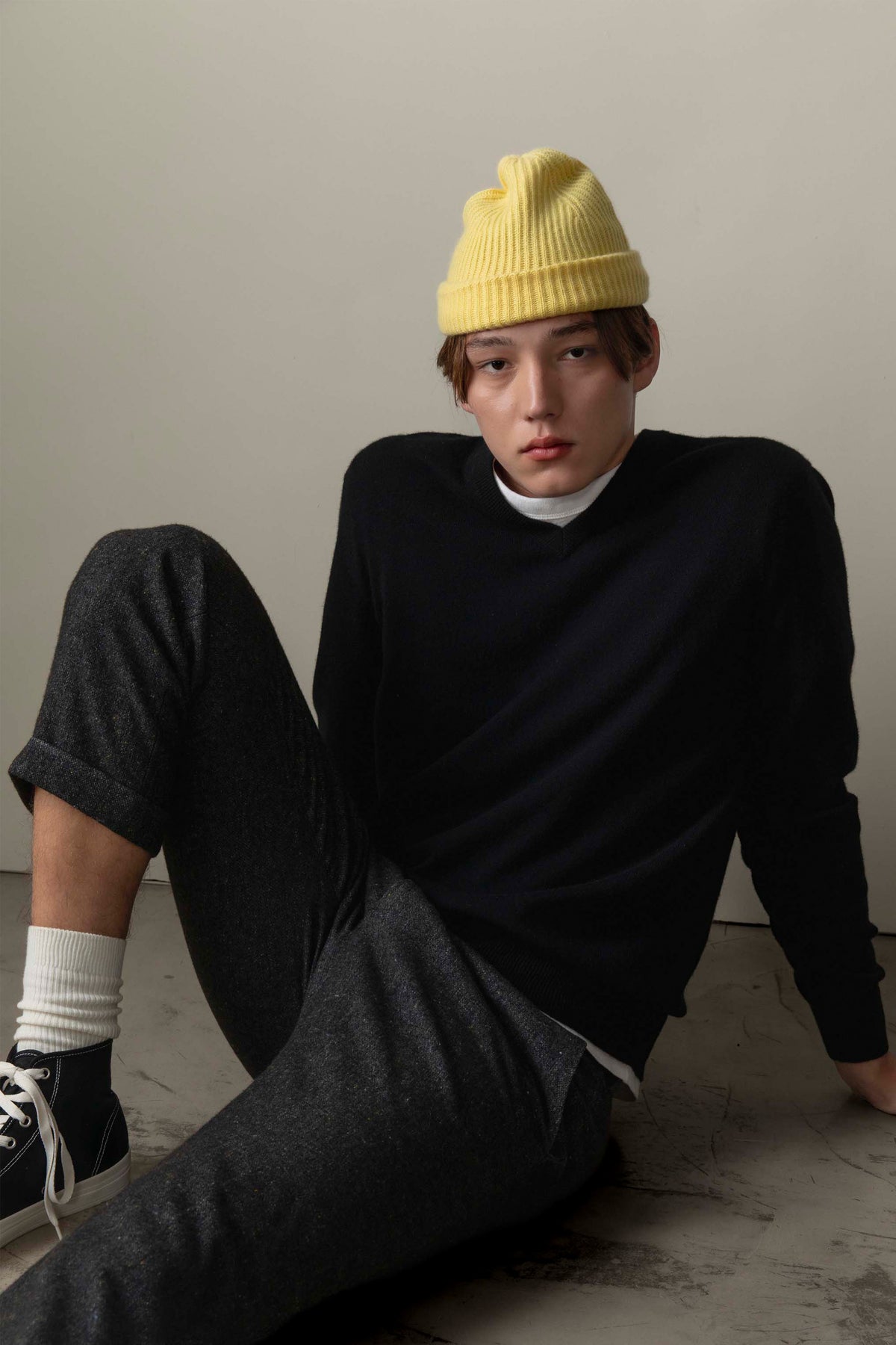 Unisex Cashmere Ribbed Beanie Hat in lemon yellow, worn by model seated on floor, showing soft ribbed knit and cuffed brim