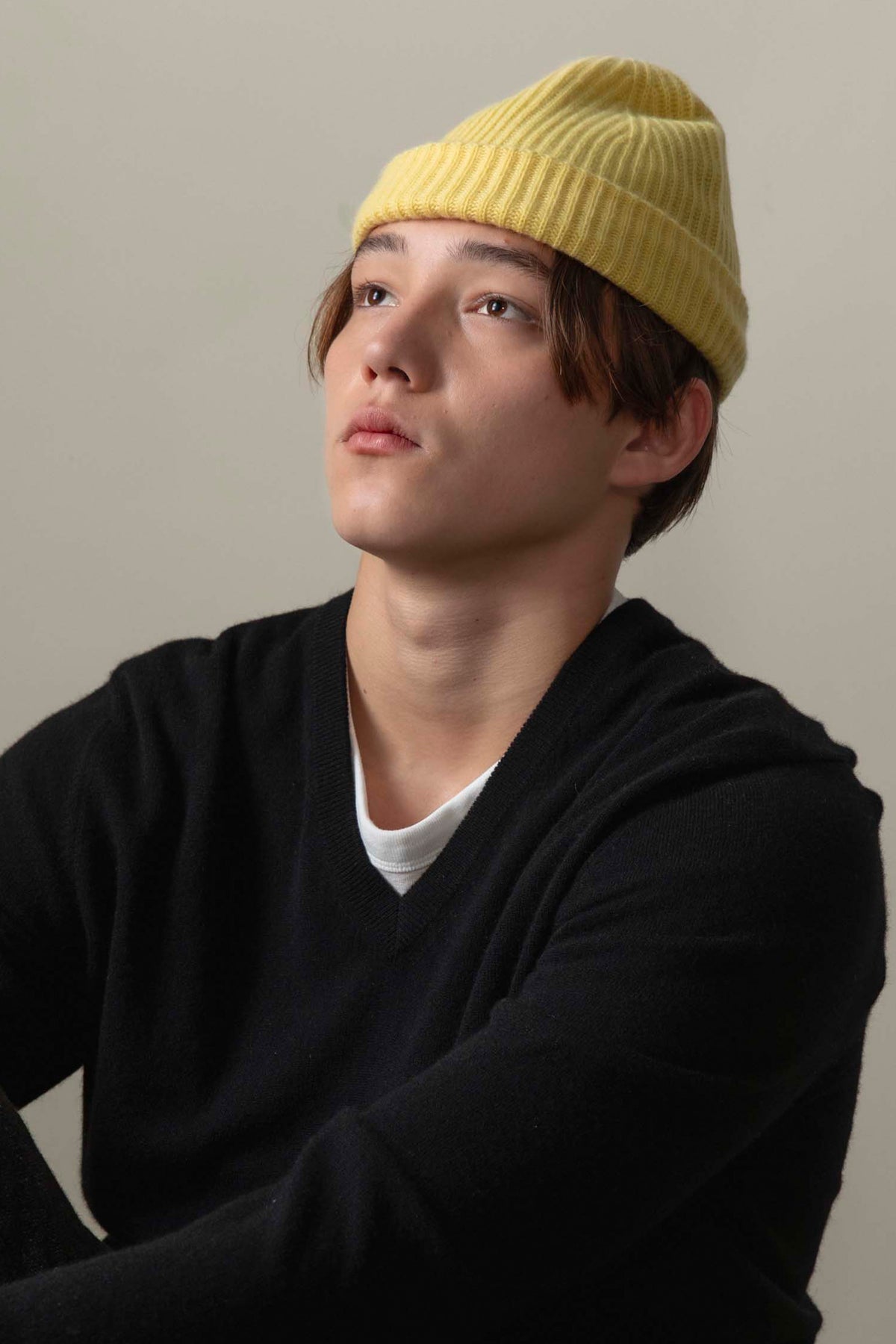 Model wearing the Unisex Cashmere Ribbed Beanie Hat in Lemon Yellow with a folded cuff, styled with a black v-neck sweater