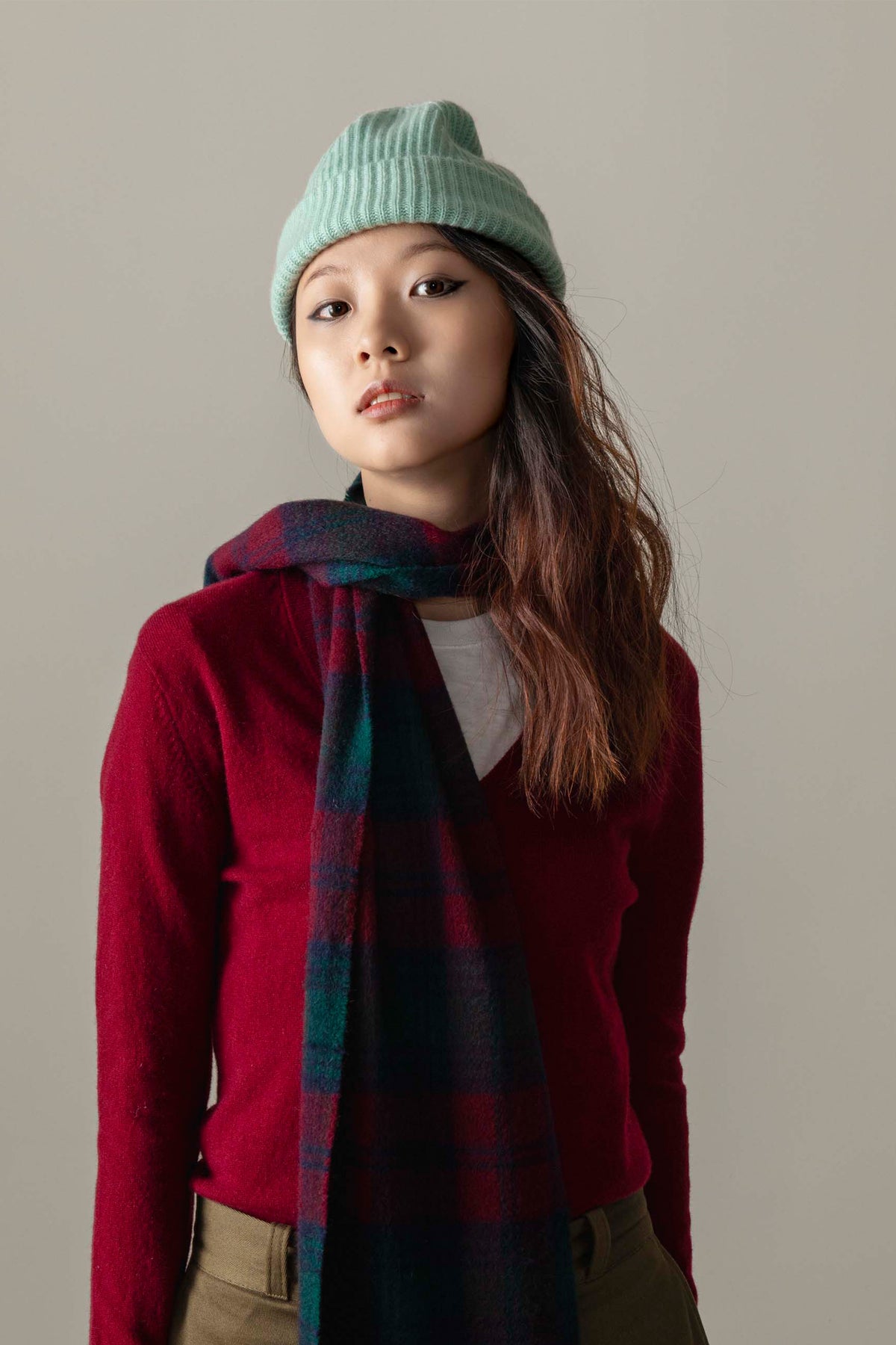 Unisex Cashmere Ribbed Beanie Hat in Brume worn by model styled with a burgundy sweater and plaid scarf