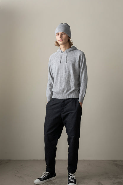 Model wearing the Unisex Cashmere Hoodie in Light Grey, full-length front view styled with dark trousers and a matching grey beanie
