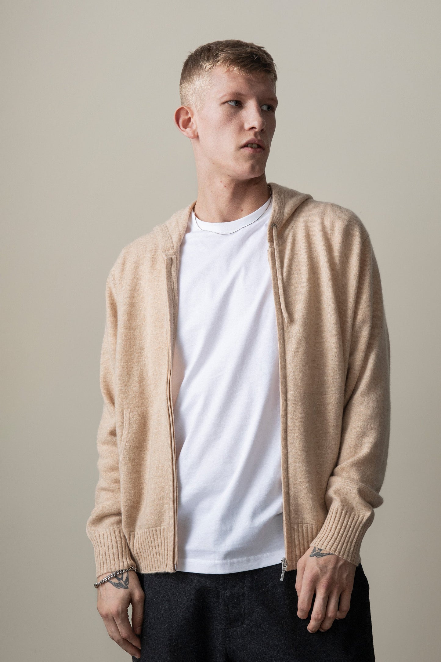 Model wearing the Unisex Cashmere Zip Hoodie in Vicuna open over a white t-shirt, showing the front zip and ribbed cuffs