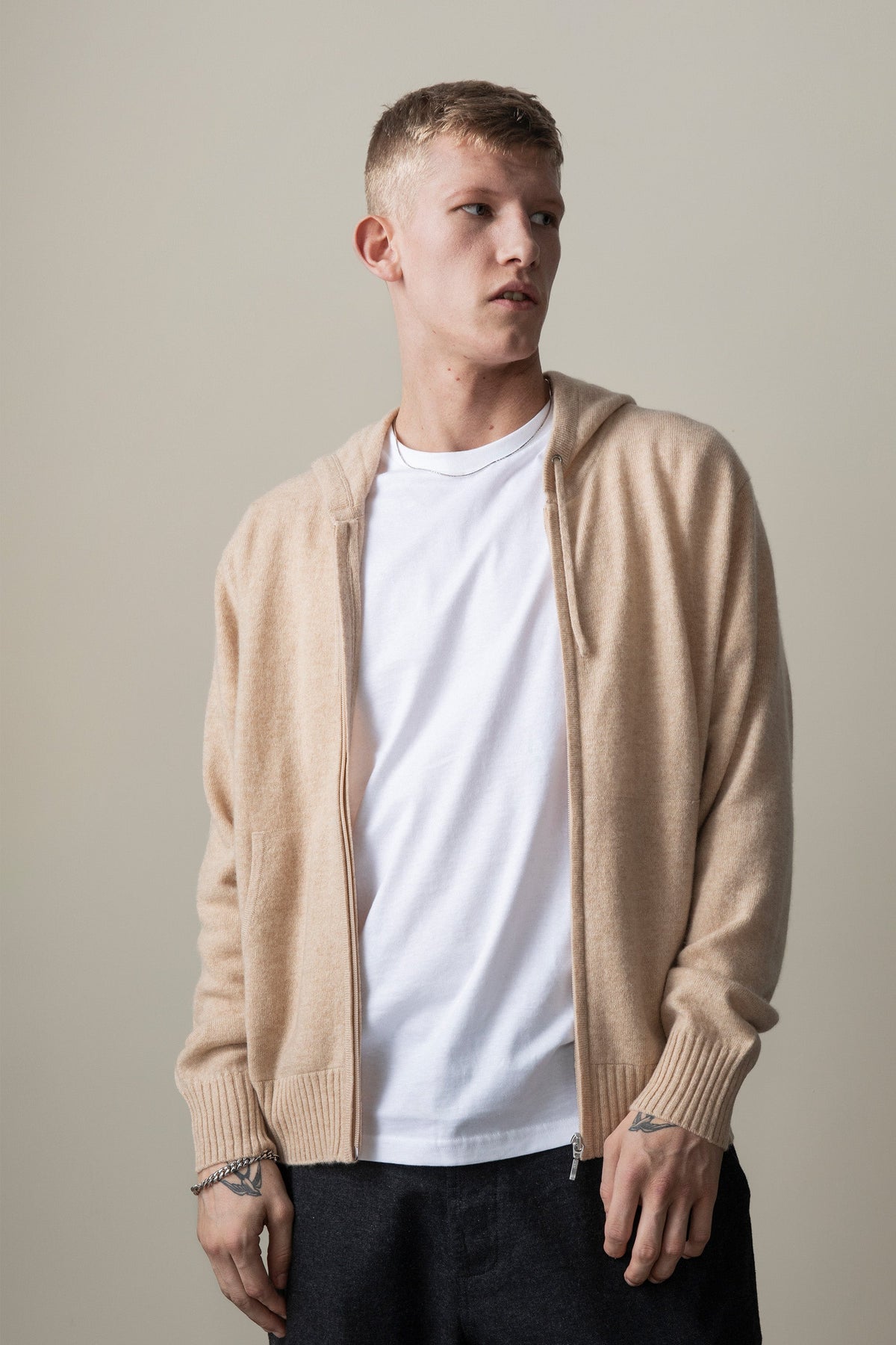 Model wearing the Unisex Cashmere Zip Hoodie in Vicuna open over a white t-shirt, showing the front zip and ribbed cuffs