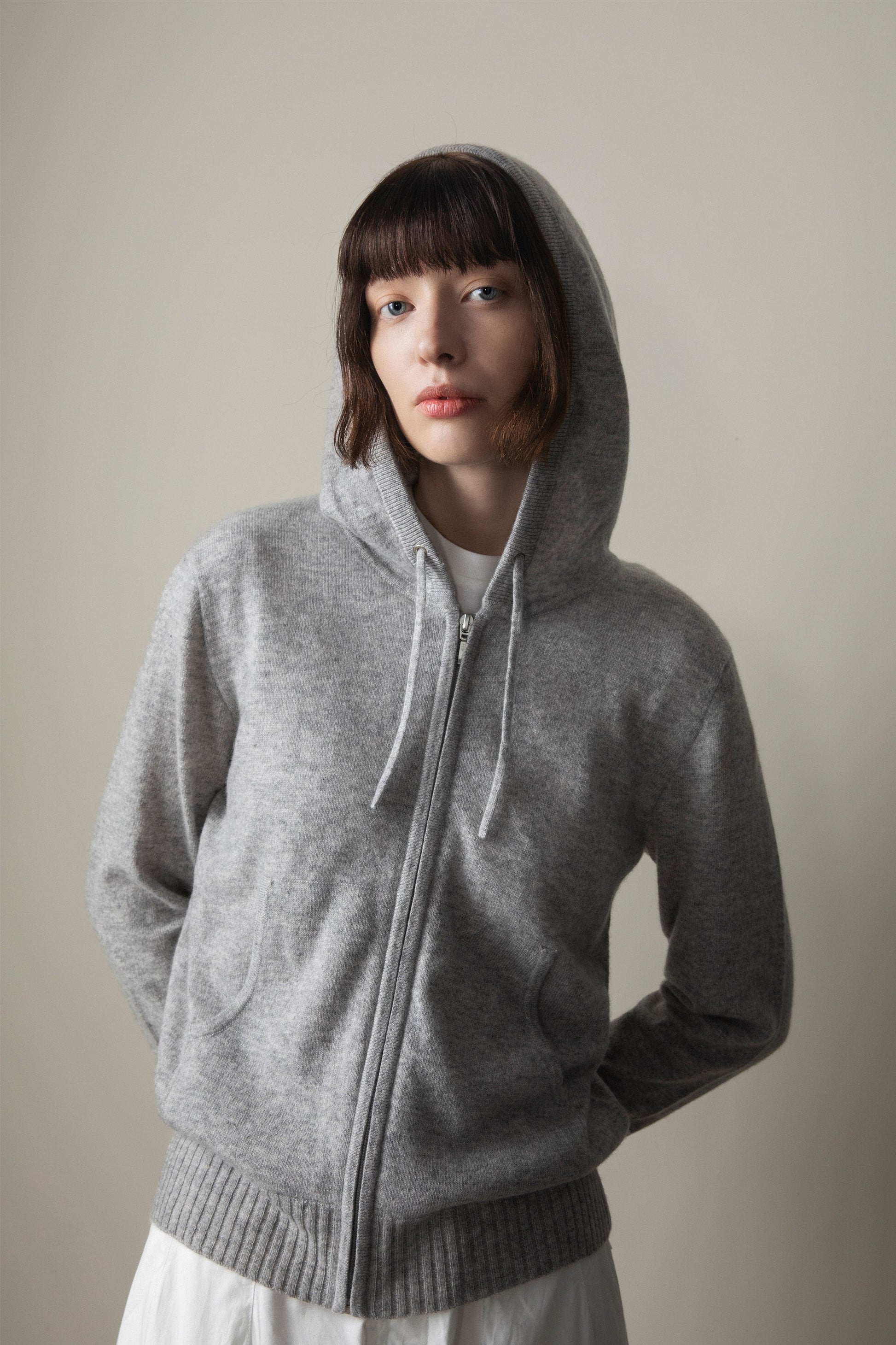 Model wearing Unisex Cashmere Zip Hoodie in Light Grey with hood up, showing front zip and kangaroo pocket detail