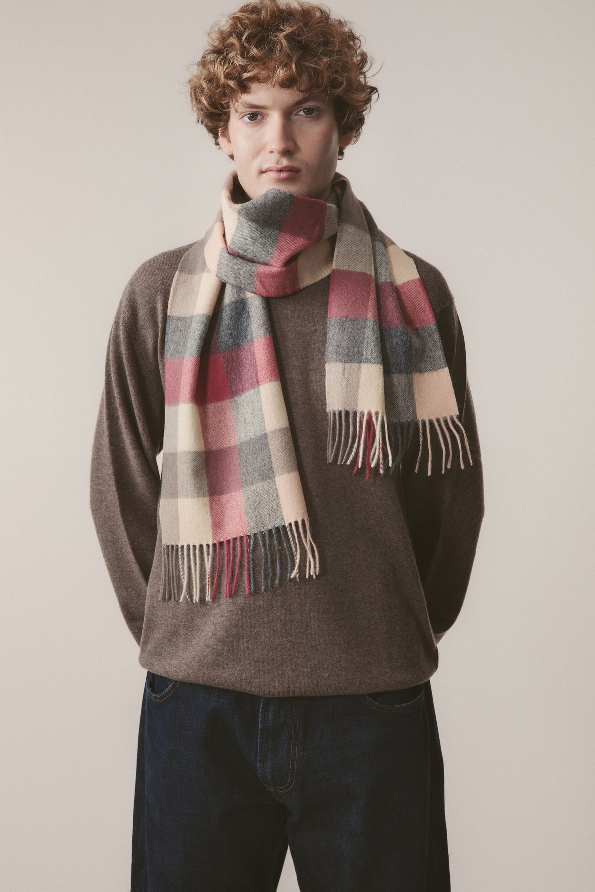5 Square Check Lambswool Scarf in Grey Rose worn looped around neck, showing pink, grey, and cream check pattern with fringe