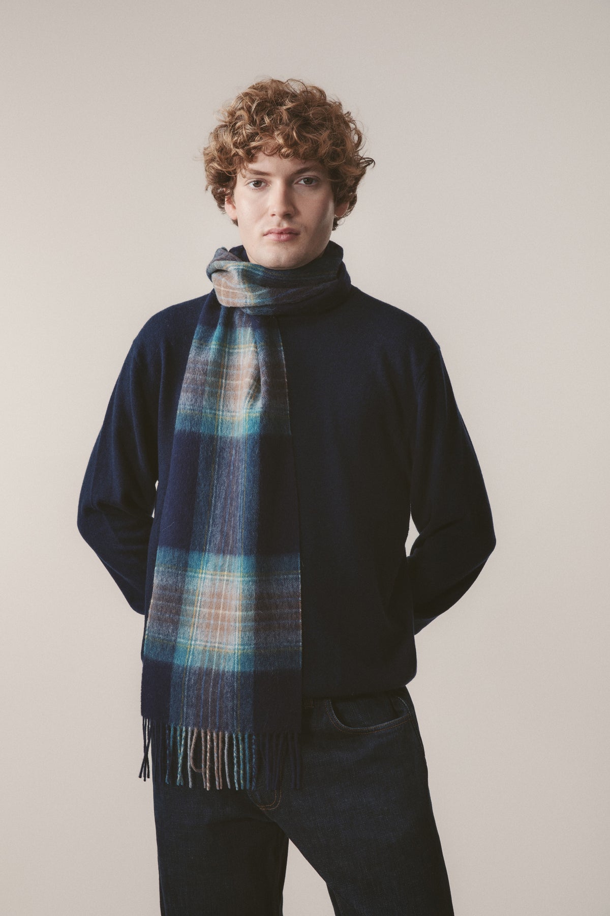 Heritage Tartan Lambswool Scarf in Holyrood worn by model, featuring navy and teal plaid pattern with fringed ends