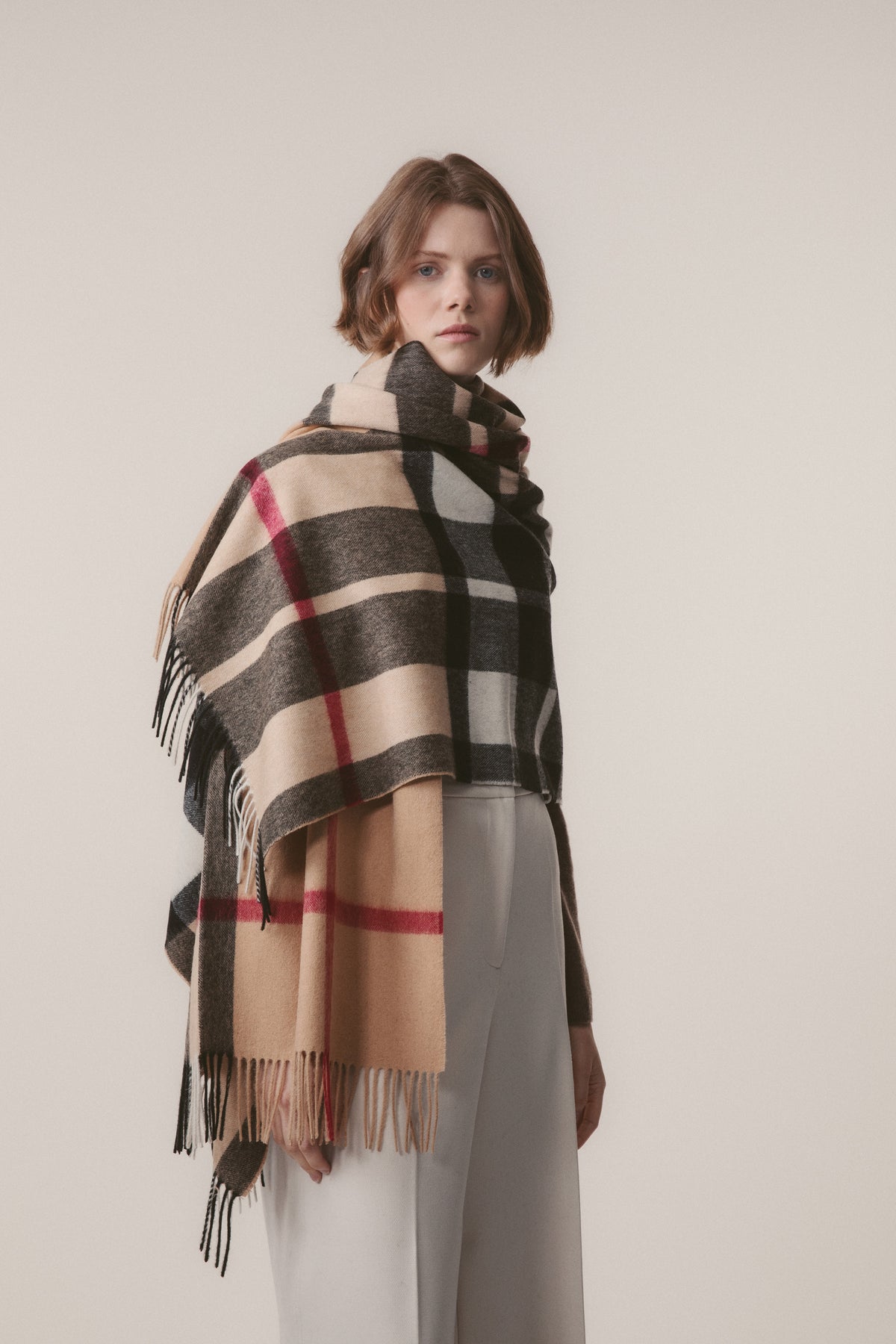 Model wearing Exploded Camel Thompson Lambswool Stole draped over shoulders, showing full check pattern with fringed edges