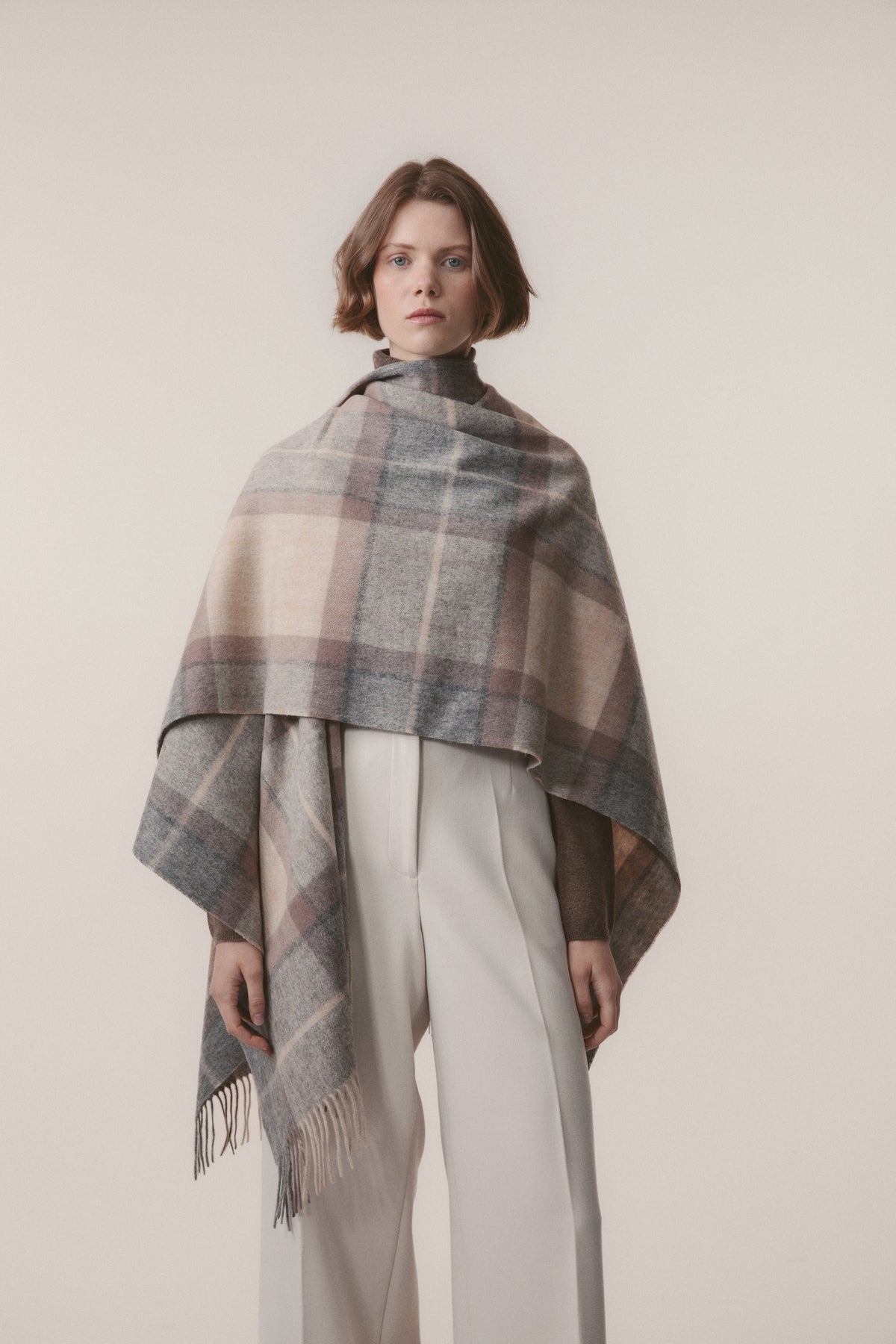 Heritage Tartan Lambswool Wrap in Mackellar Natural draped over shoulders as a shawl, showing full plaid pattern and fringed edges