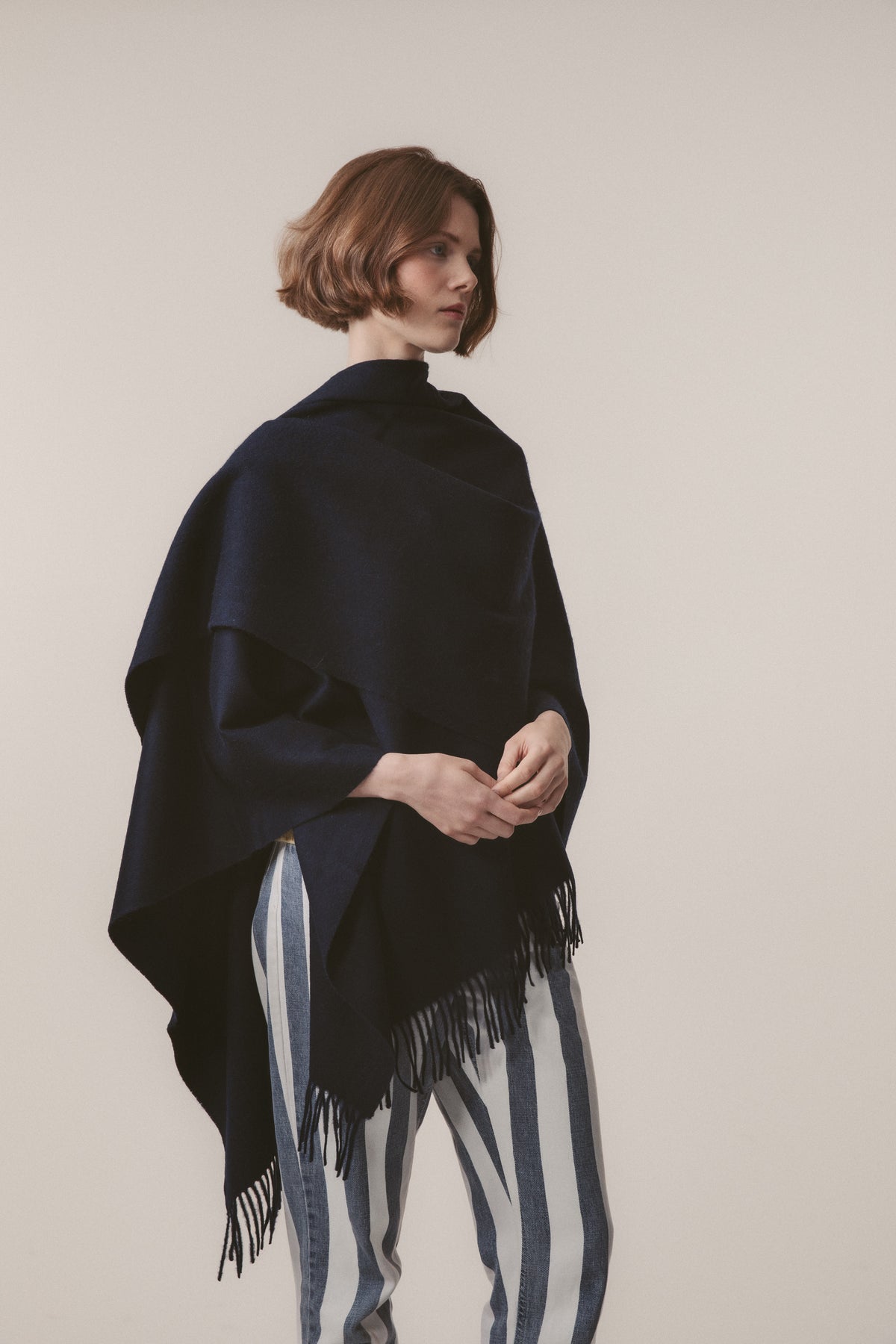 Solid Lambswool Wrap in Dark Navy worn draped over shoulders, featuring fringed edges and open-front styling