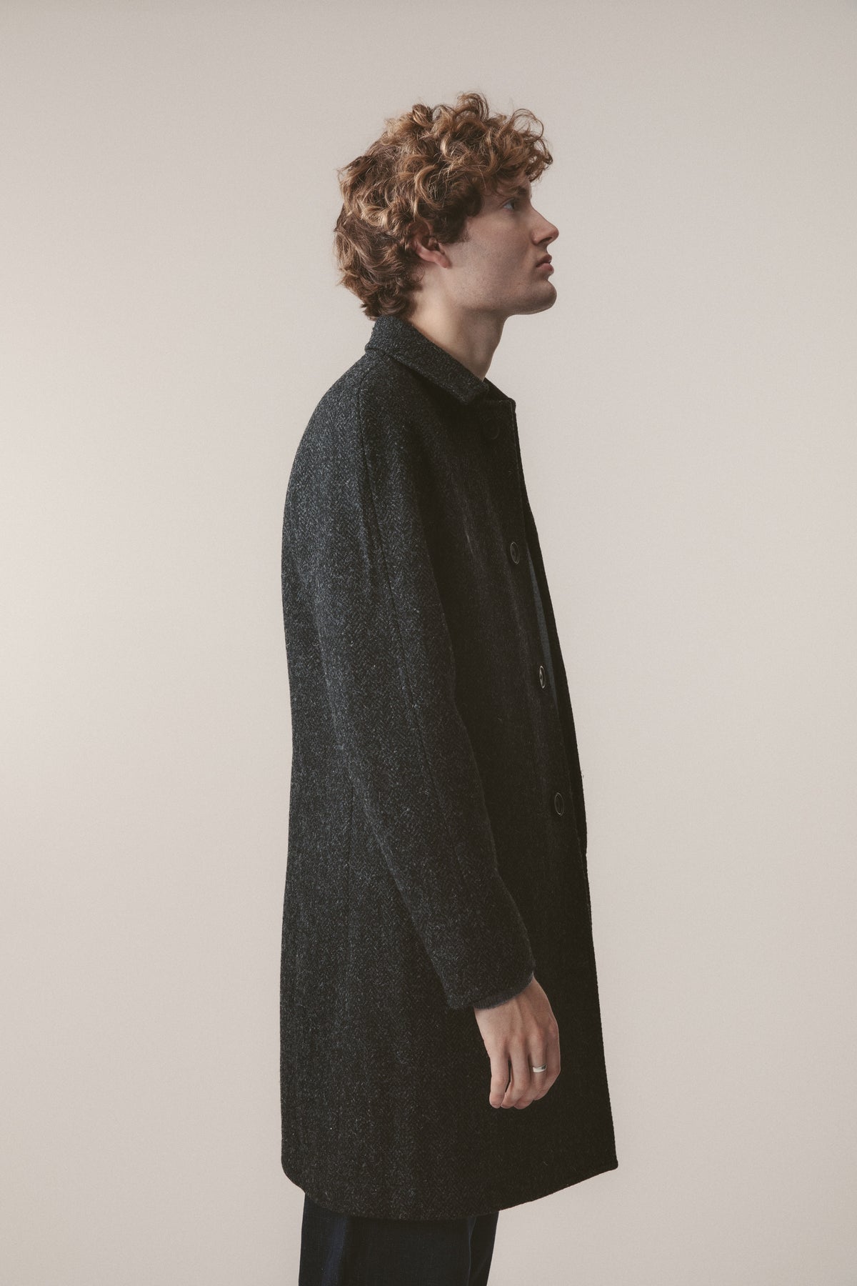 Side profile view of the Men's Harris Tweed Ottavio Pea Coat in deep charcoal, showing the mid-length cut and button placket