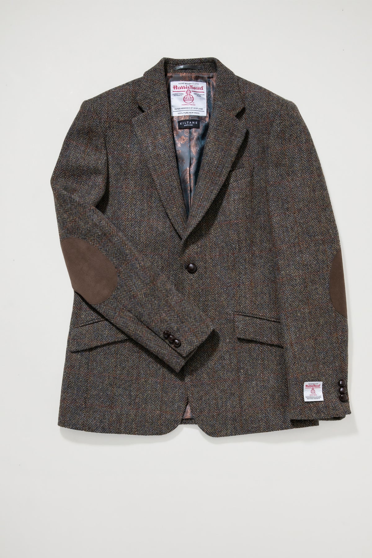 Men's Harris Tweed Patrick Jacket in brown check laid flat, showing suede elbow patches, patterned lining, and Kiltane label