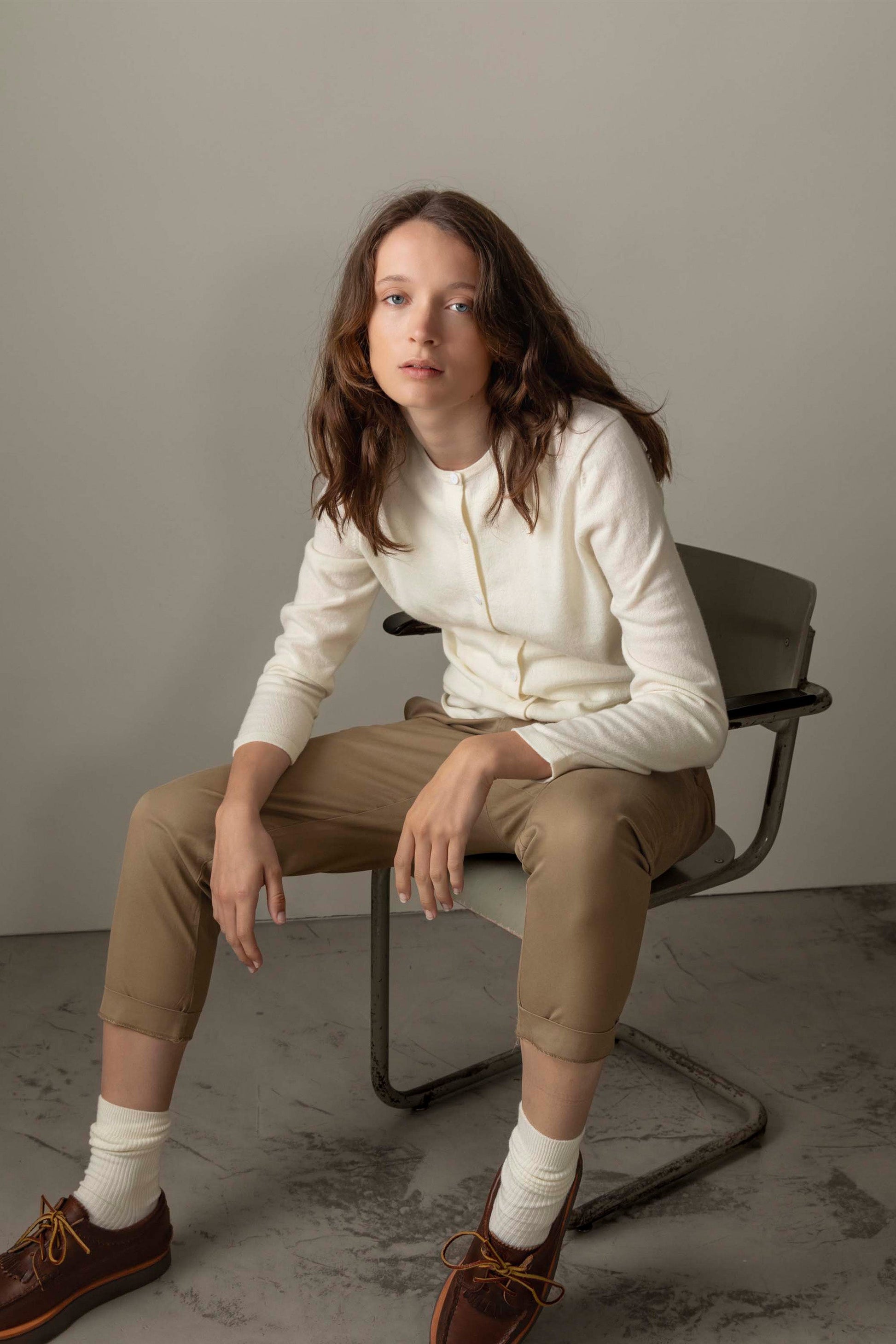 Model seated wearing the Women's Cashmere High Button Cardigan in Soft Cream, showing relaxed fit and front button placket