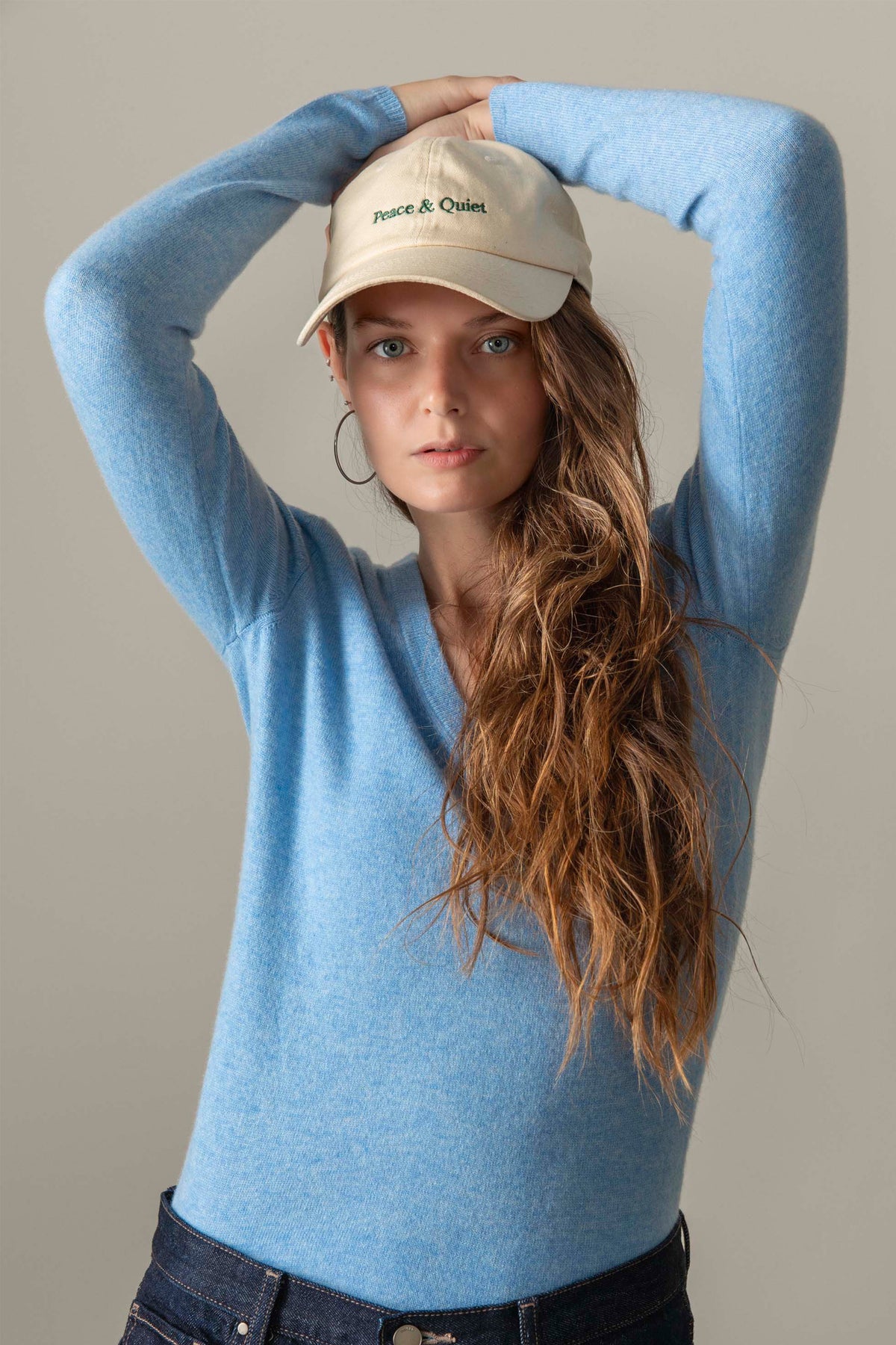 Model wearing Women's Cashmere V Neck Jumper in Glacier blue, styled with jeans and a cap, showing the soft knit texture
