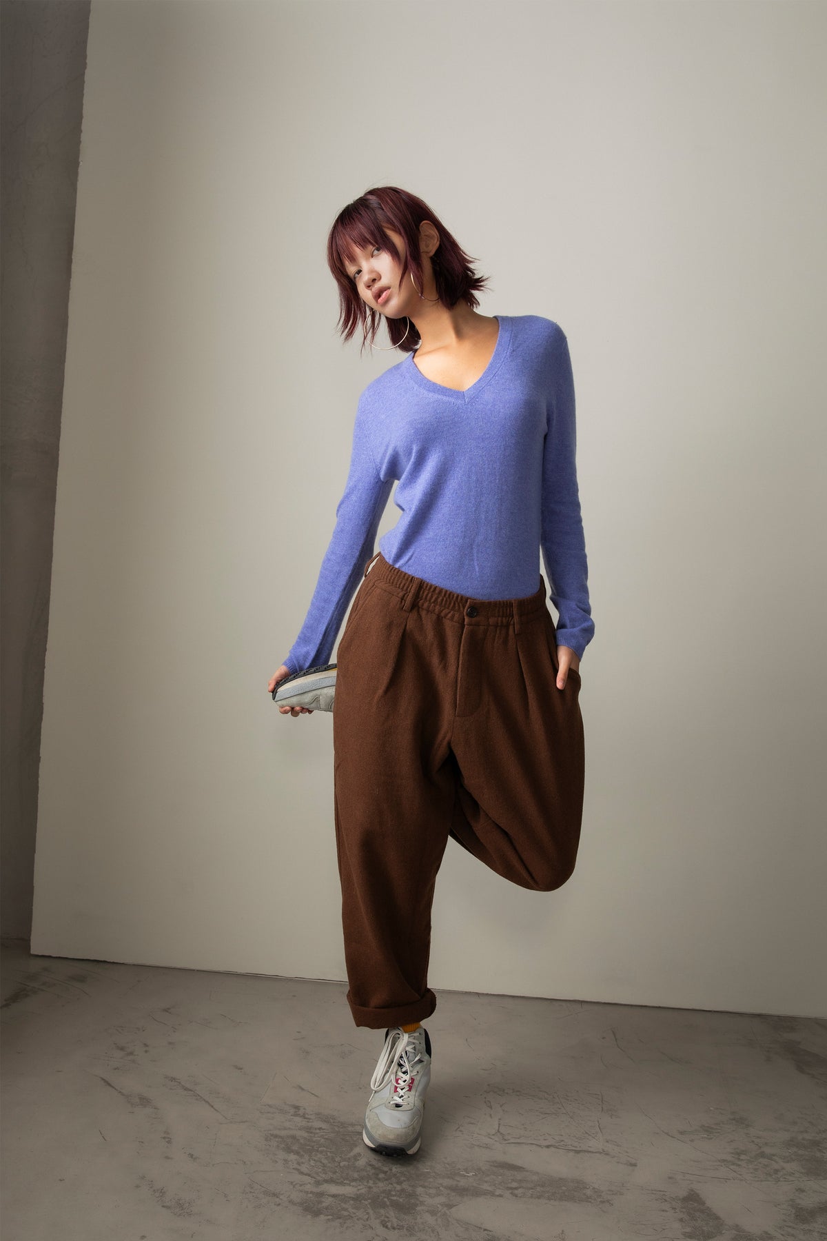 Women's Cashmere V Neck Jumper in Wisteria, a soft periwinkle-blue lightweight knit with ribbed neckline, styled with brown trousers