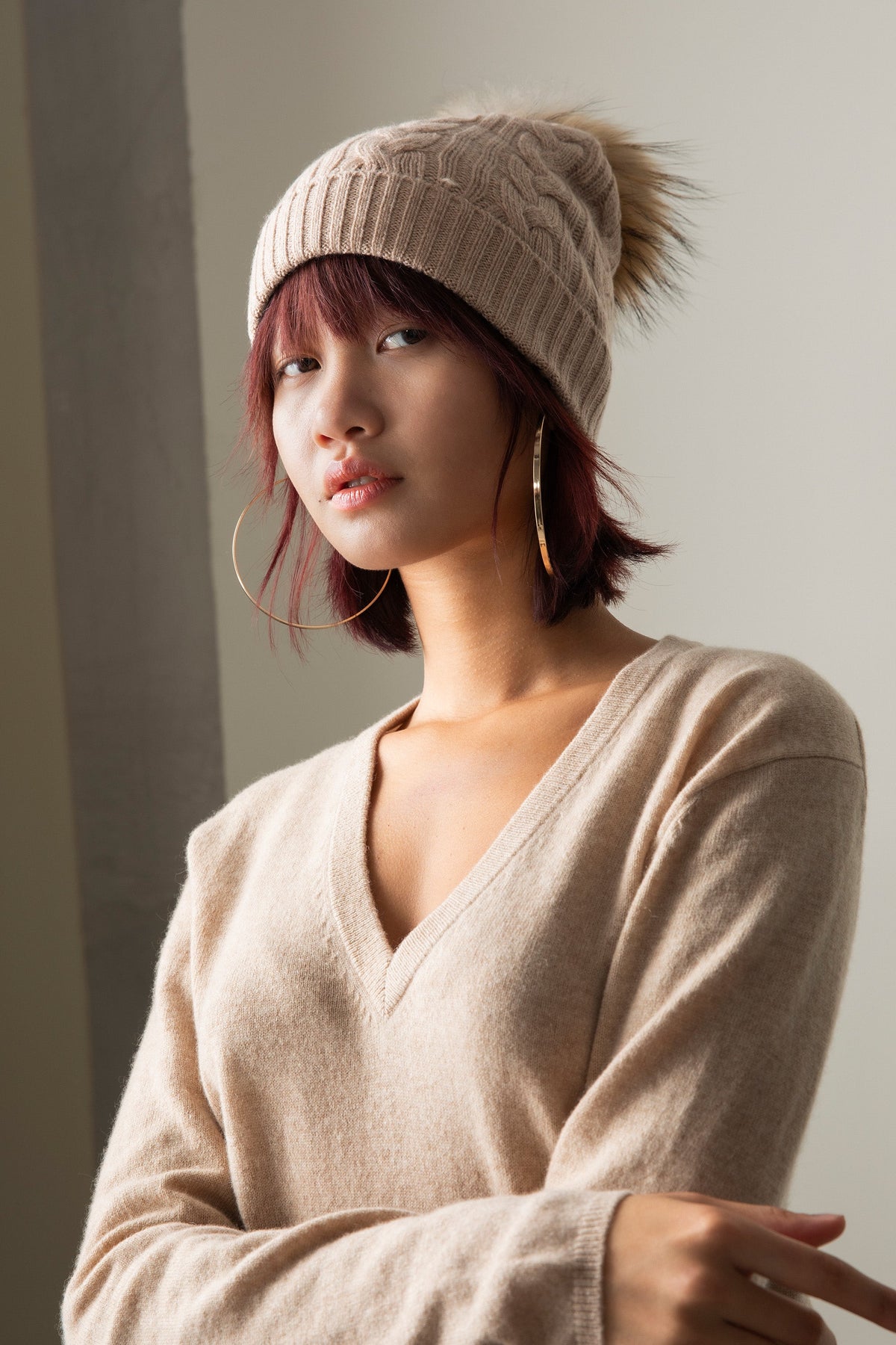 Model wearing Women's Cashmere V Neck Jumper in Vicuna, styled with a cable-knit beanie showing the relaxed V-neckline