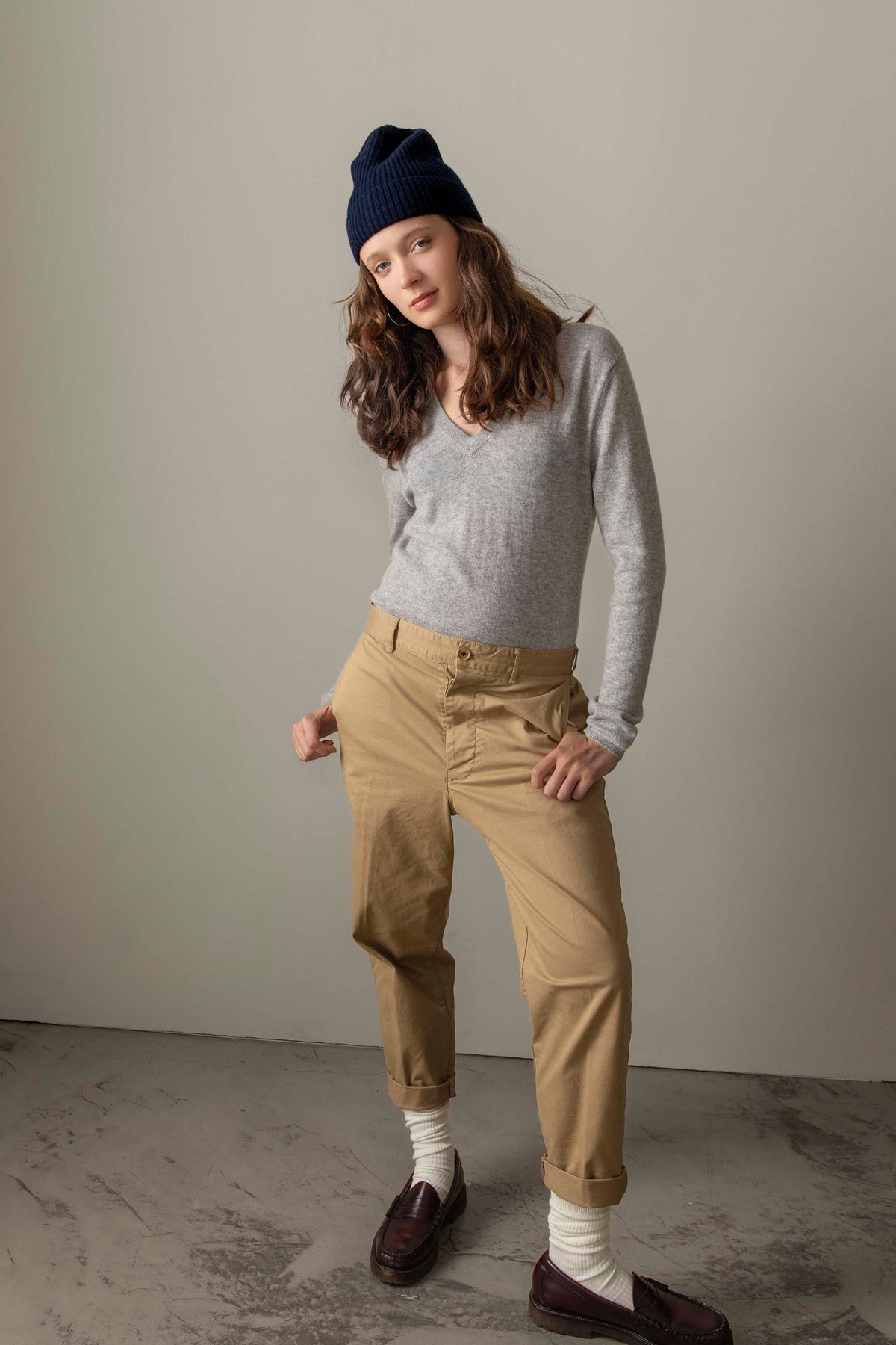 Women's Cashmere V Neck Jumper in light grey styled with tan chinos, navy beanie, and burgundy loafers — full outfit view