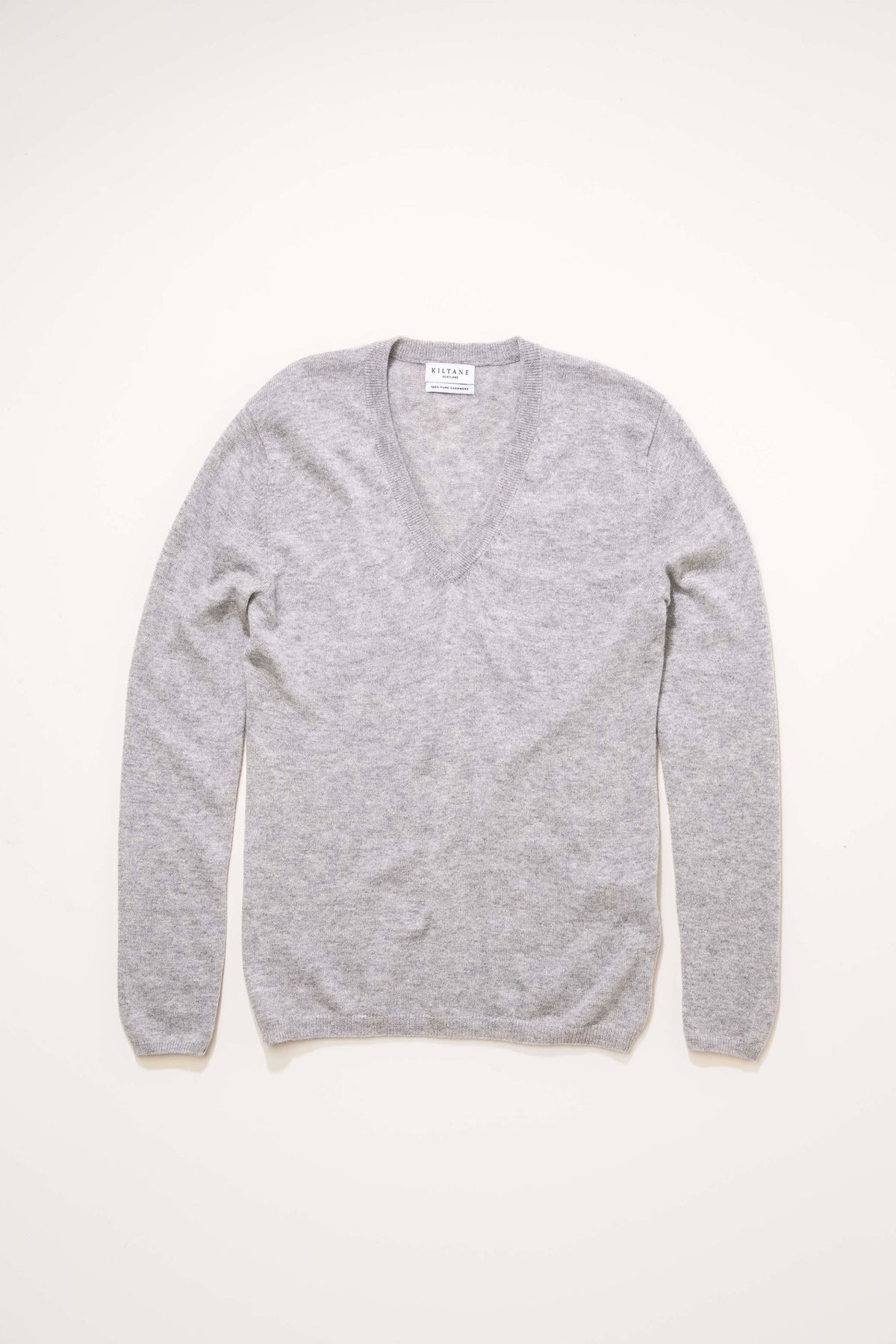 Kiltane Women's Cashmere V Neck Jumper in light grey laid flat, showing full front with ribbed V-neckline and long sleeves