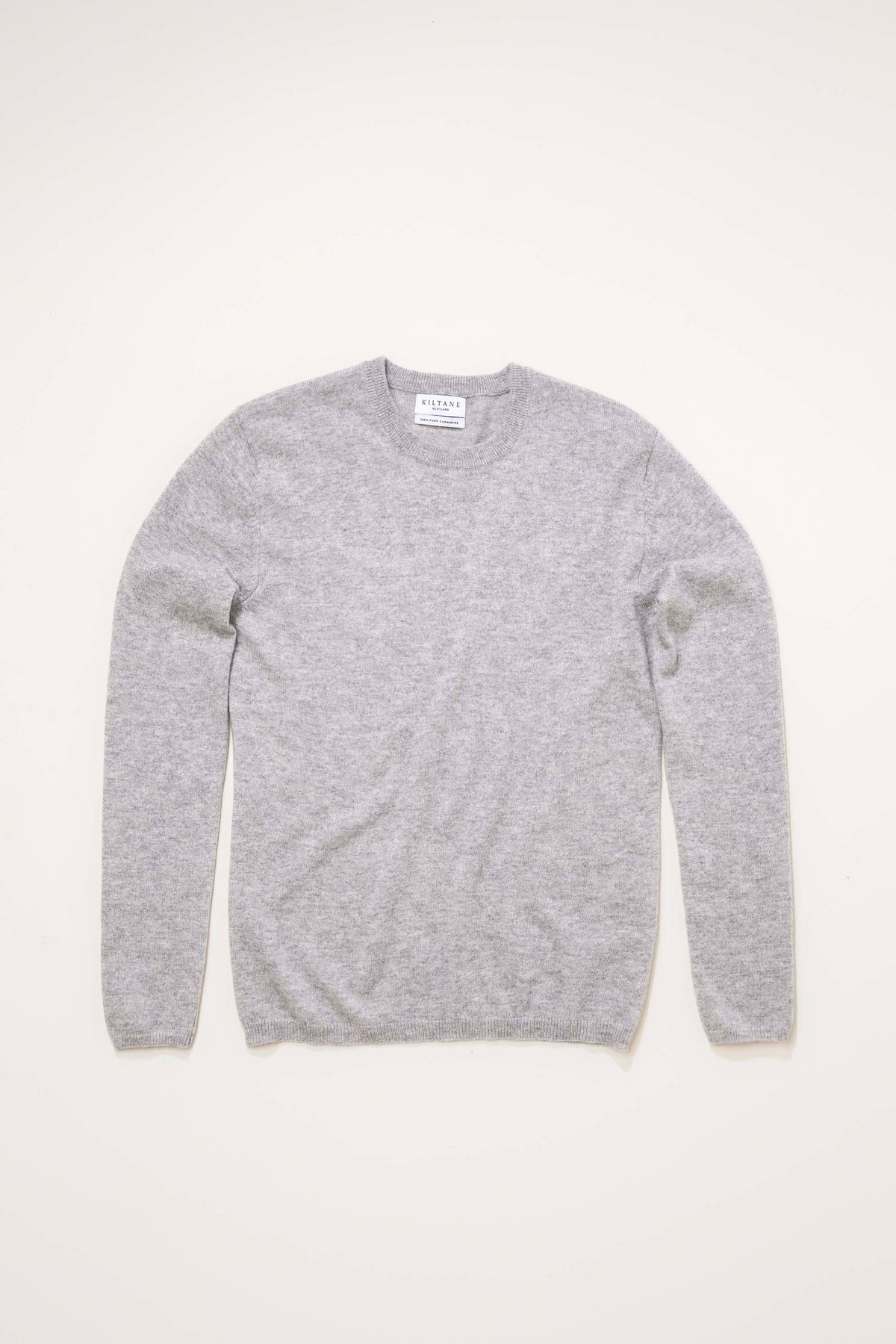 Kiltane Women's Cashmere Crew Neck Jumper in light grey laid flat, showing full front with ribbed neckline and cuffs