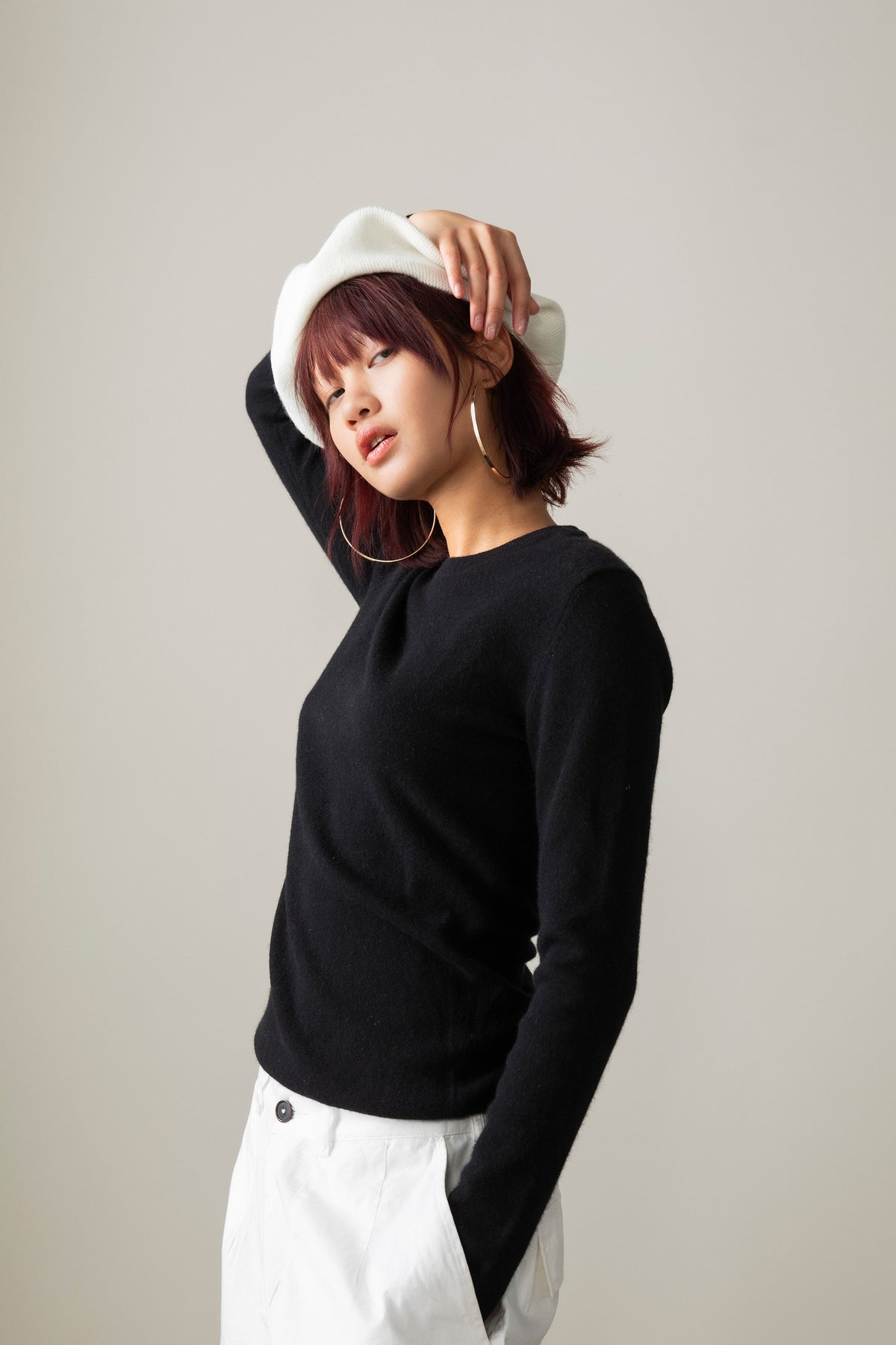 Women's Cashmere Crew Neck Jumper in black, side profile showing slim fit and long sleeves, styled with white trousers