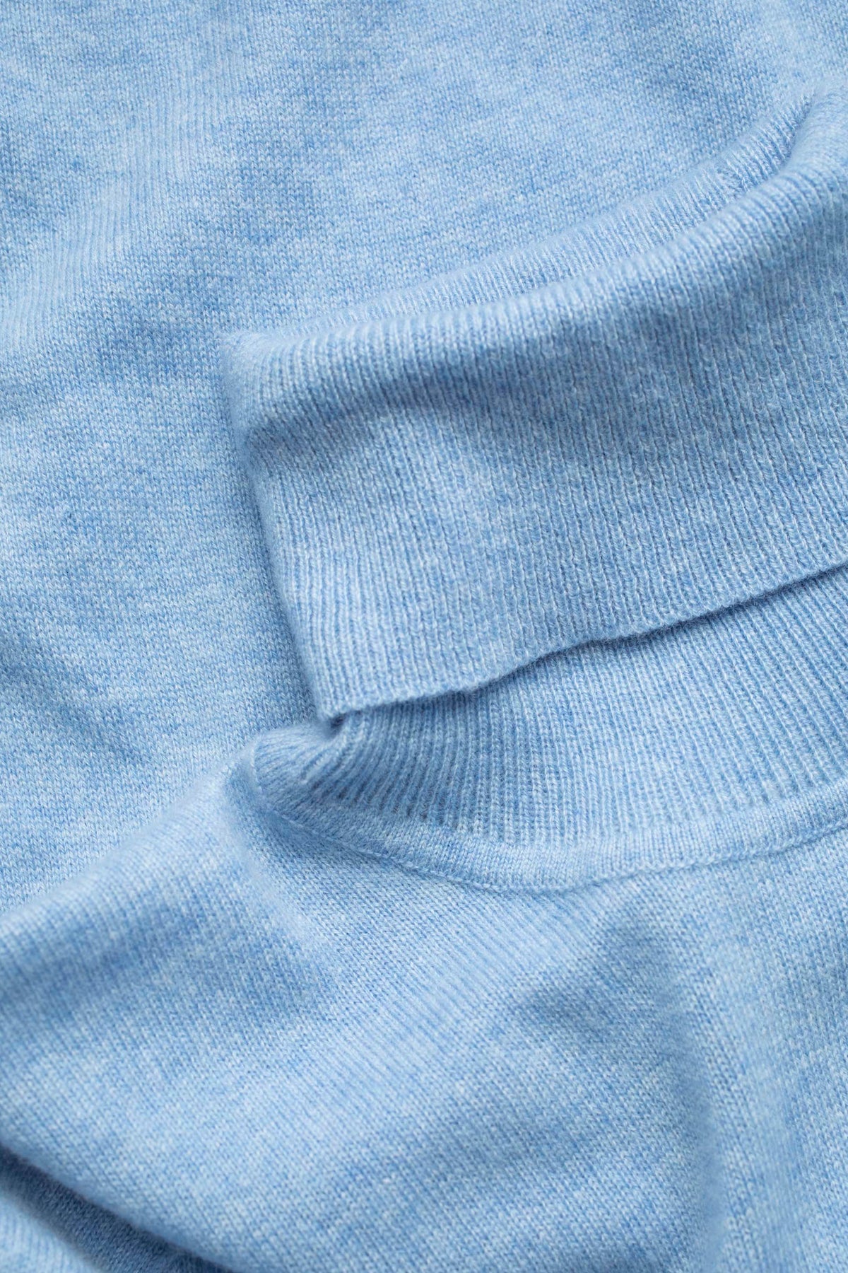 Close-up of the soft knit texture and folded polo neck on the Women's Cashmere Polo Neck Jumper in Glacier blue