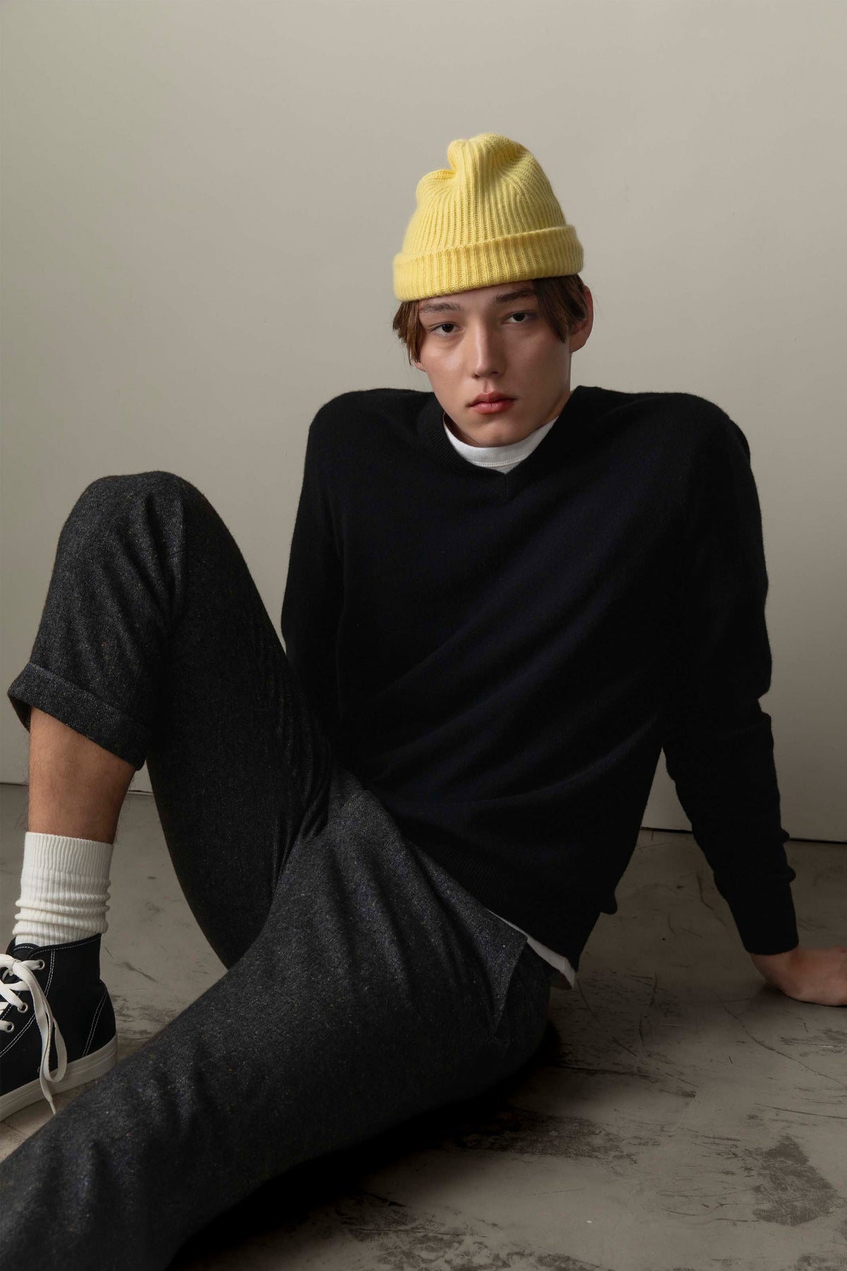 Men's Cashmere V Neck Jumper in black, lightweight knit with ribbed neckline, styled with charcoal trousers and yellow beanie