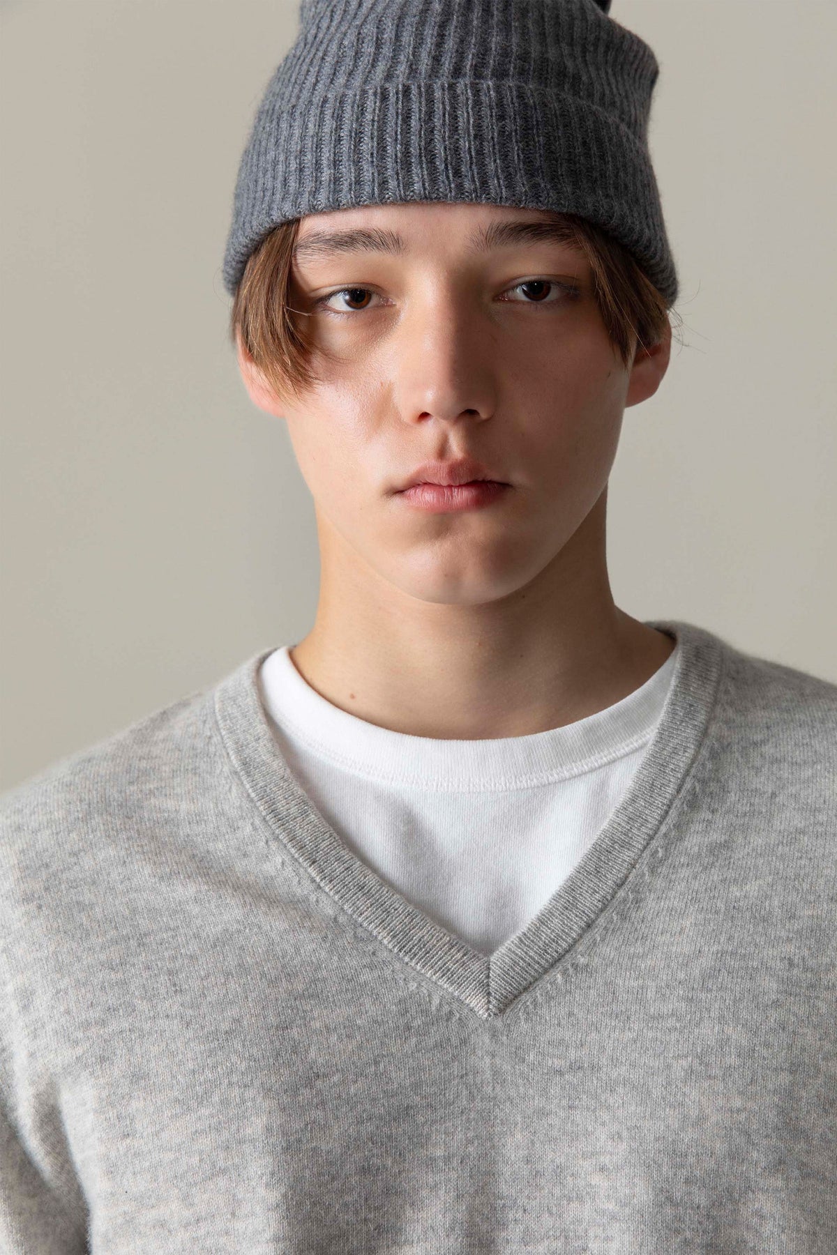 Close-up of Men's Cashmere V Neck Jumper in light grey, showing ribbed V-neckline detail layered over a white tee