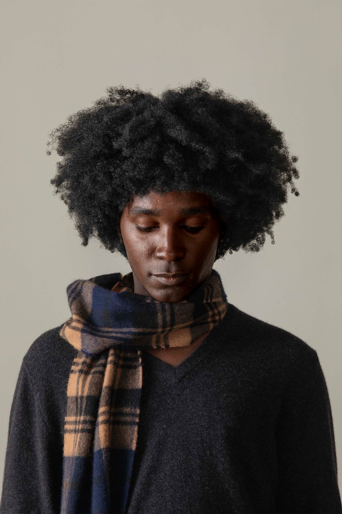 Men's Cashmere V Neck Jumper in Charcoal styled with a plaid scarf, showing the relaxed fit and V-neckline detail