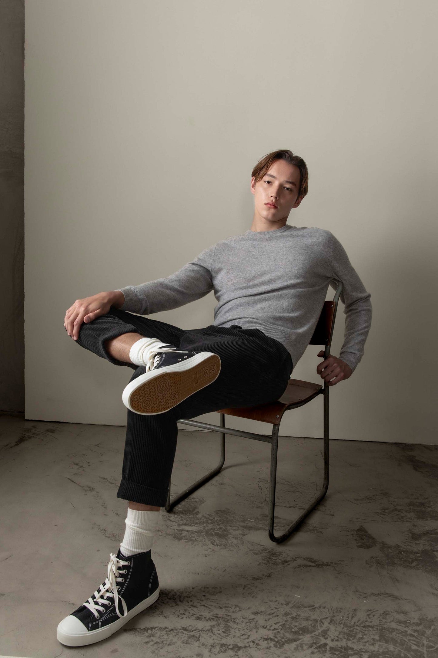 Men's Cashmere Crew Neck Jumper in light grey, slim relaxed fit, worn by model seated in a studio setting