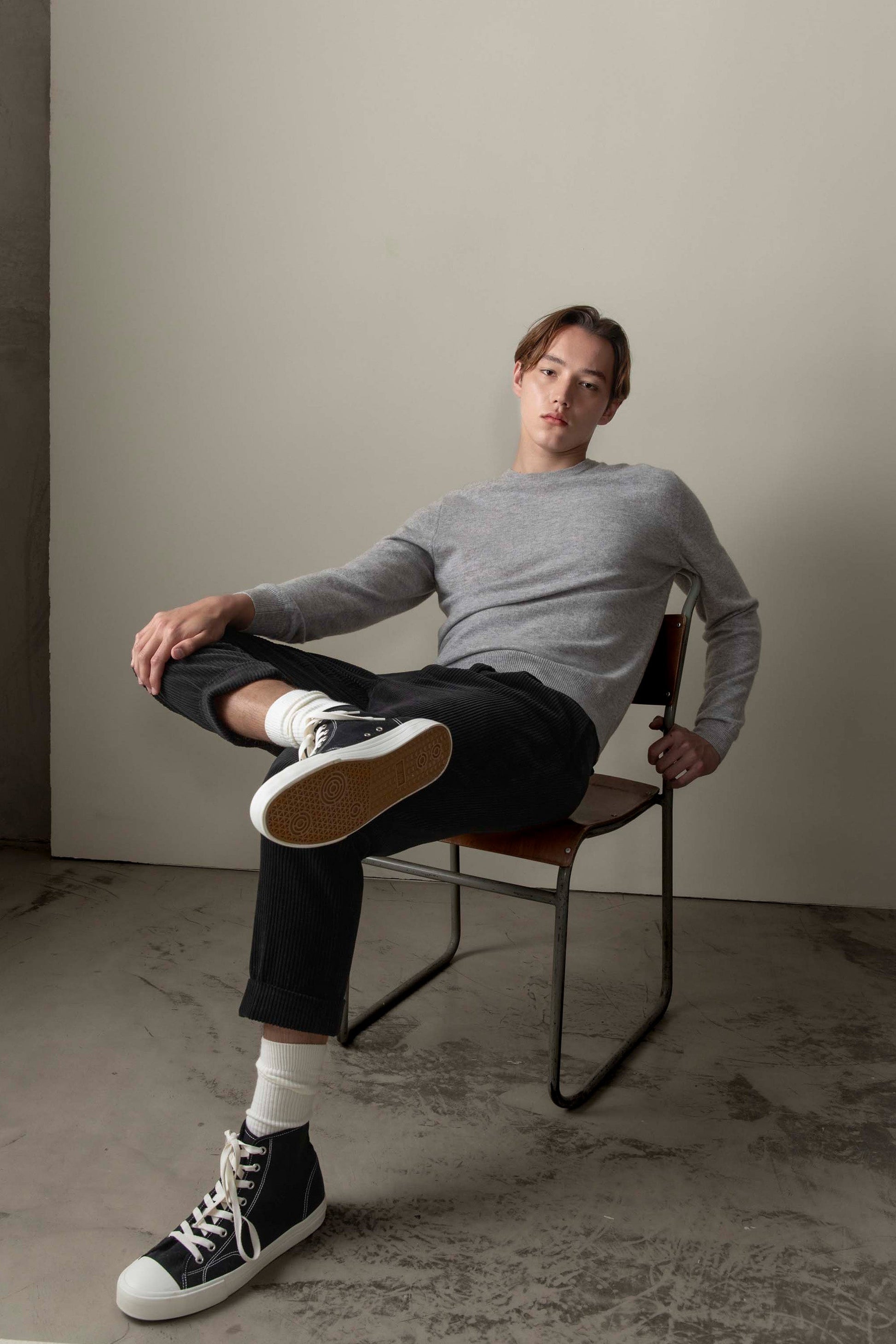 Men's Cashmere Crew Neck Jumper in light grey, slim relaxed fit, worn by model seated in a studio setting